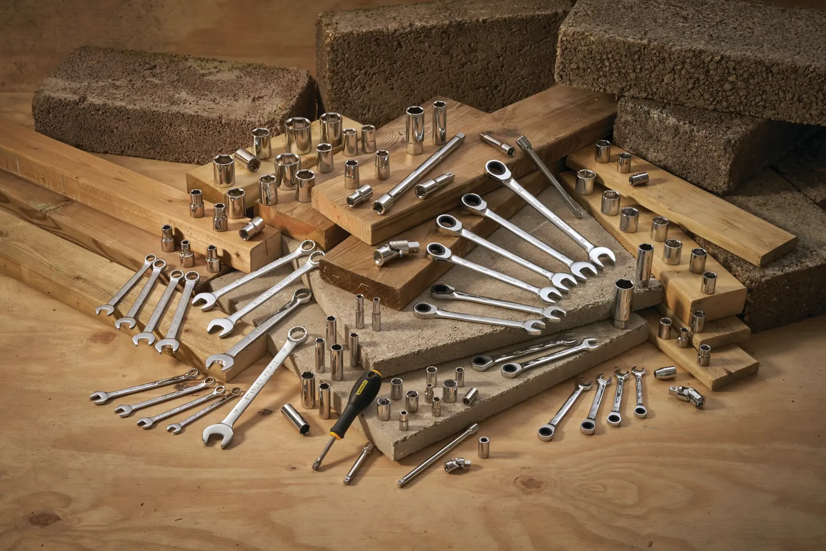 STANLEY STMT95908-0 set di chiavi, bussole, cricchetti e cacciavite disposti su legno e mattoni, vista angolata.