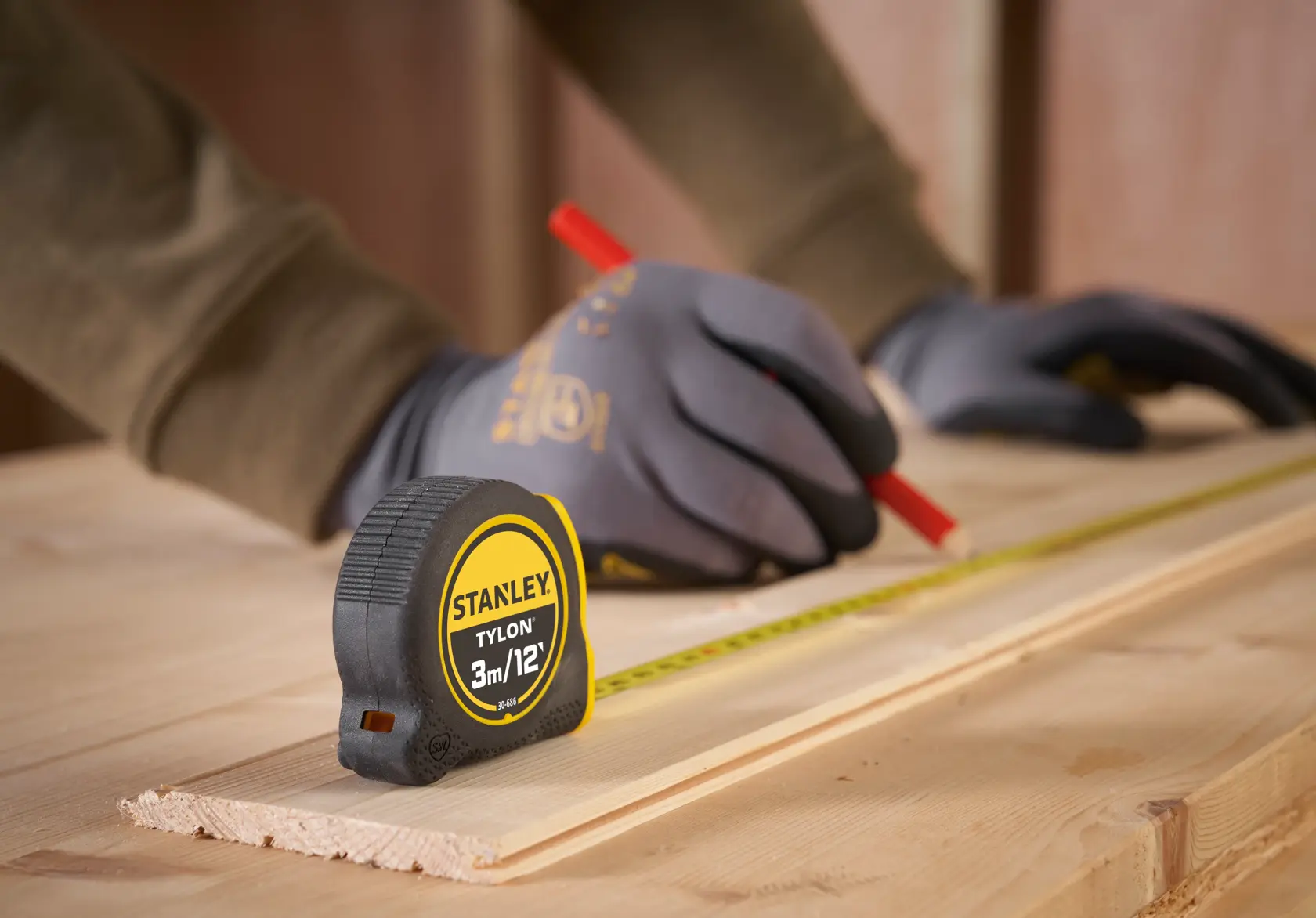STANLEY 0-30-686 metro a nastro su legno con mani guantate che segnano le misure, prodotto in uso.
