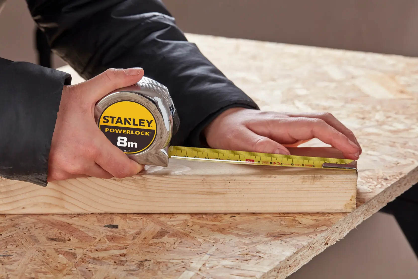 STANLEY 0-33-527 metro a nastro misura una tavola di legno su un tavolo da lavoro, fotografia ravvicinata.