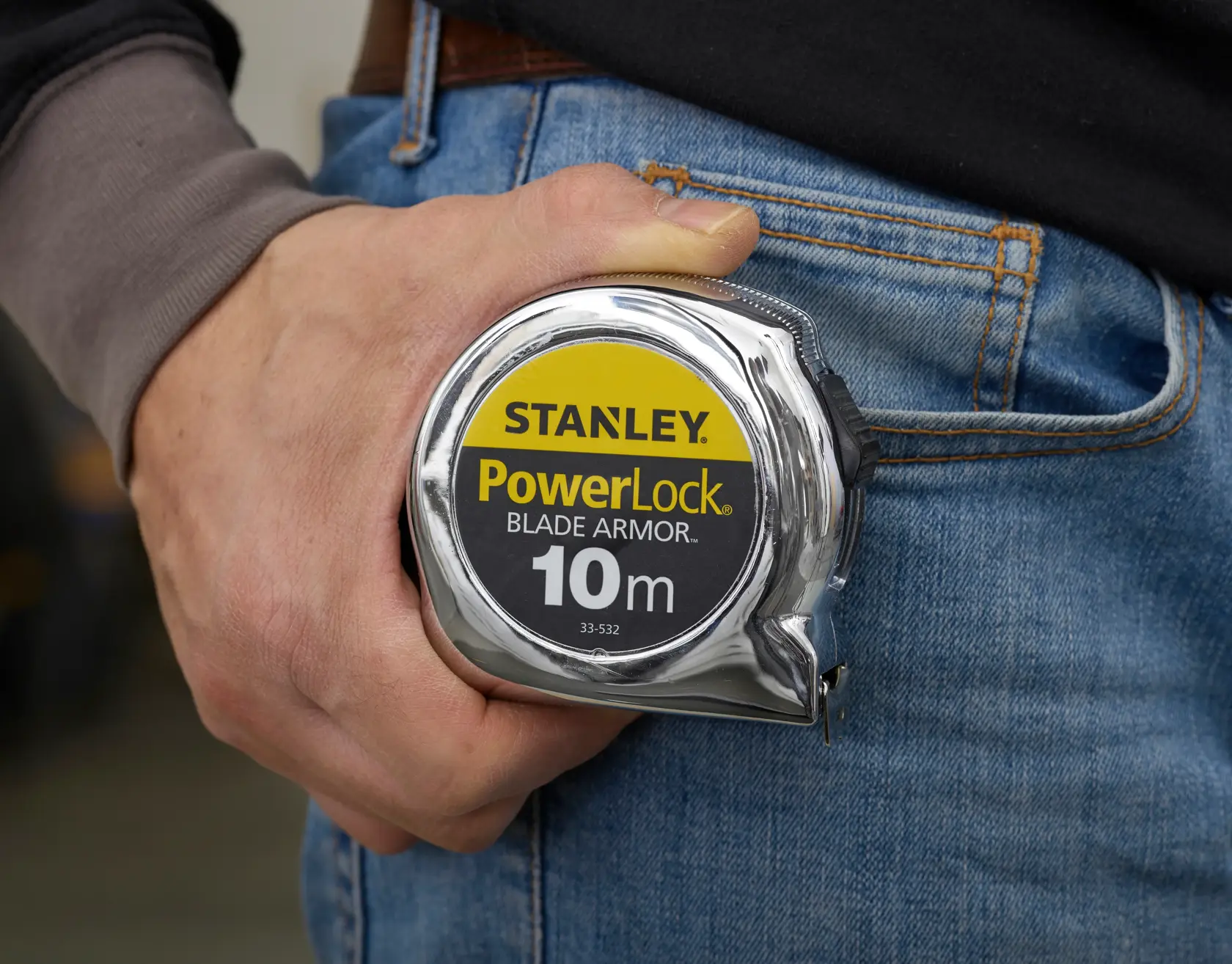 Foto di STANLEY PowerLock Blade Armor metro da 10m SKU 0-33-532 tenuto accanto a jeans blu.