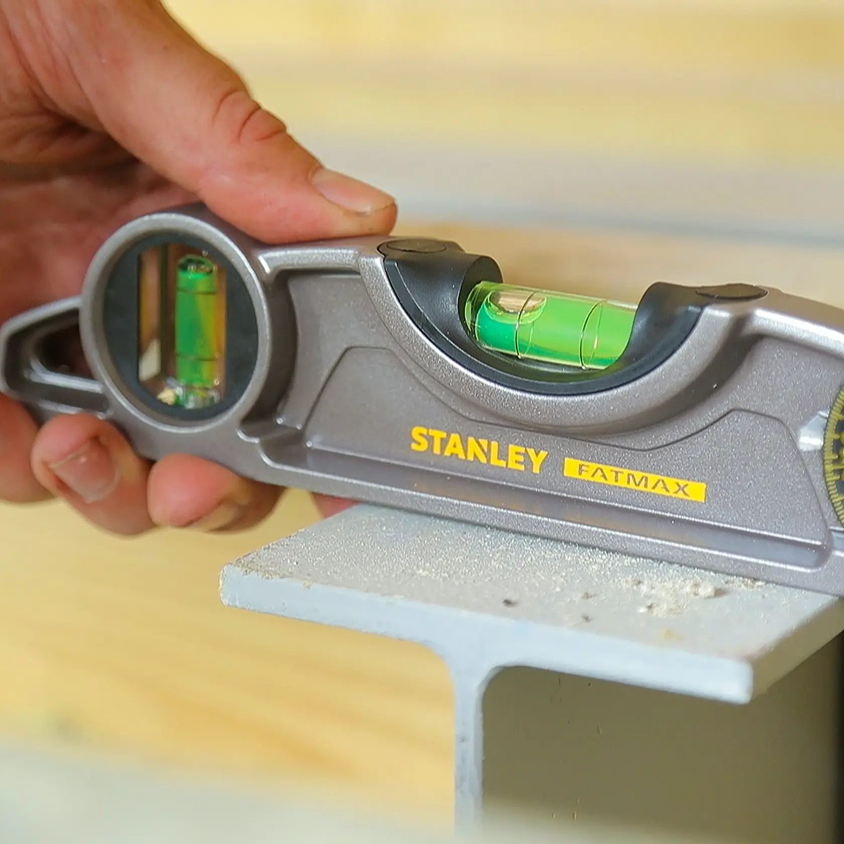 Foto del livello STANLEY 0-43-609 FATMAX in uso, corpo argento, fiale a bolla visibili, tenuto in mano.