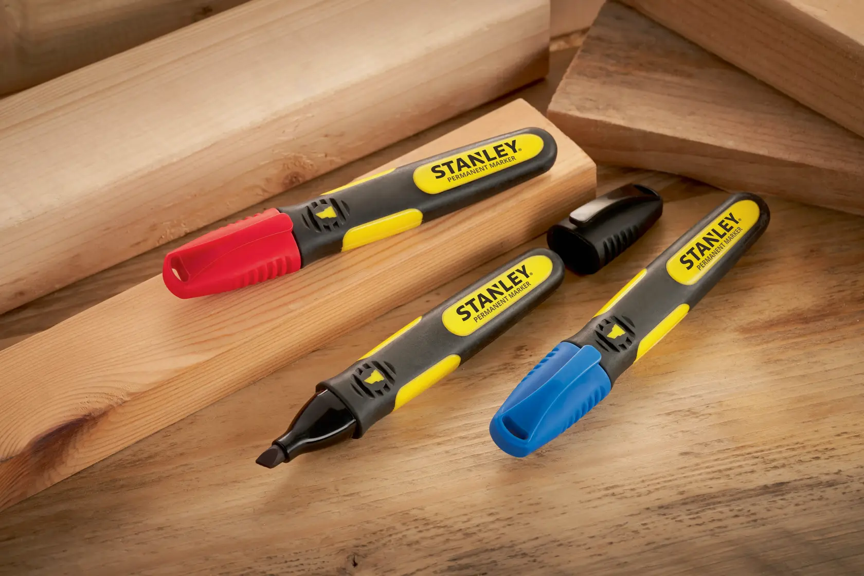 STANLEY SKU 0-47-315 pennarelli permanenti con cappucci rossi, blu e neri su assi di legno, vista angolata.