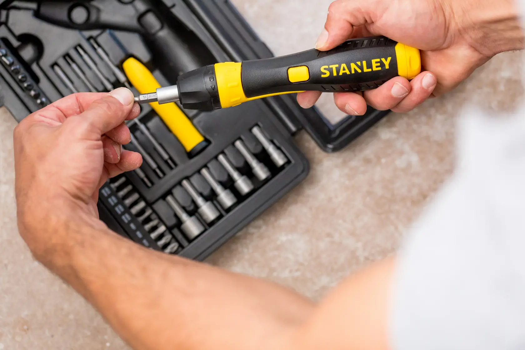 STANLEY 0-63-038 set cacciavite a cricchetto con manico nero e giallo, persona inserisce una punta, vista dall'alto.