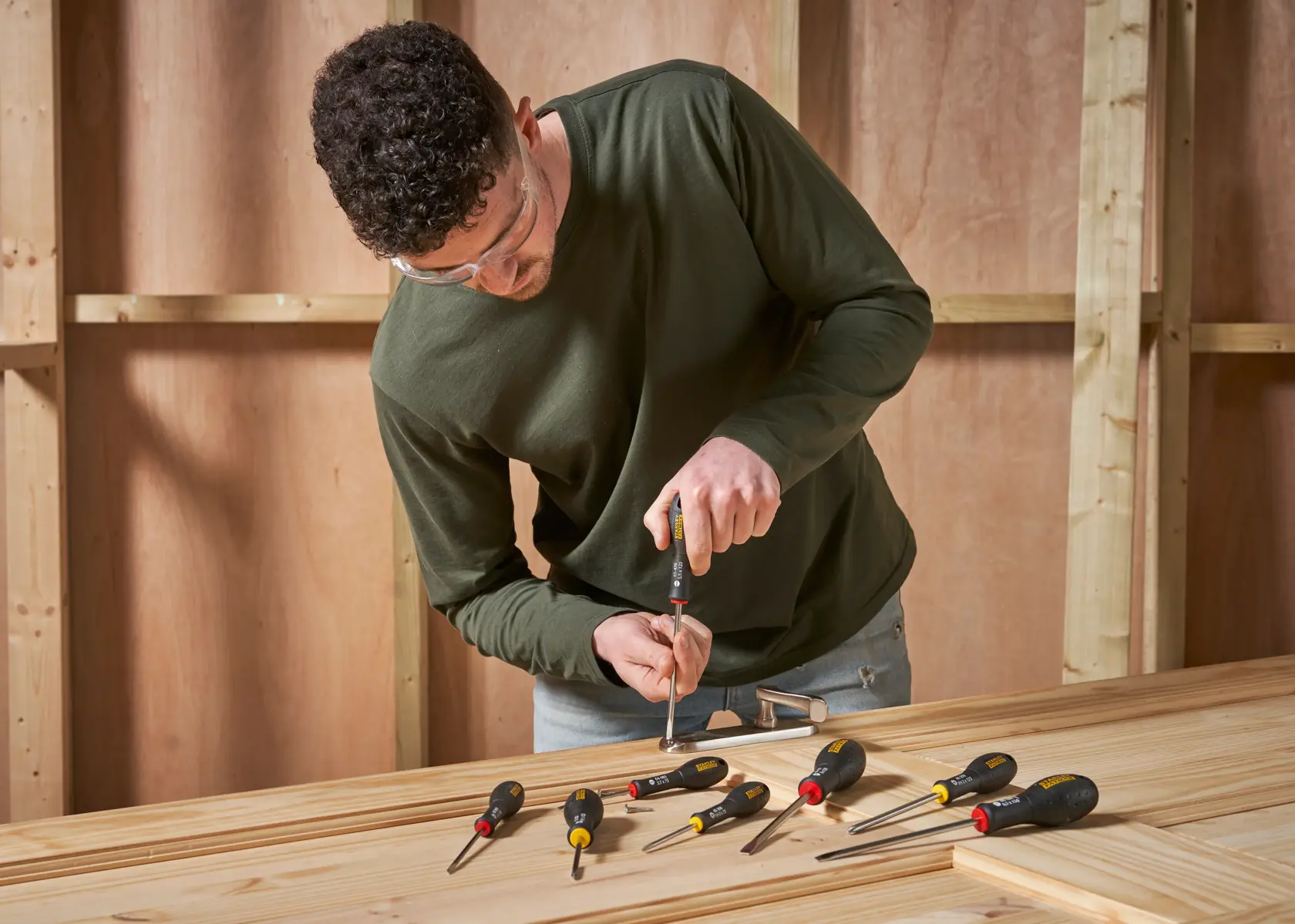 Foto di set di cacciaviti STANLEY 0-65-437 su tavolo di legno con operaio in laboratorio.