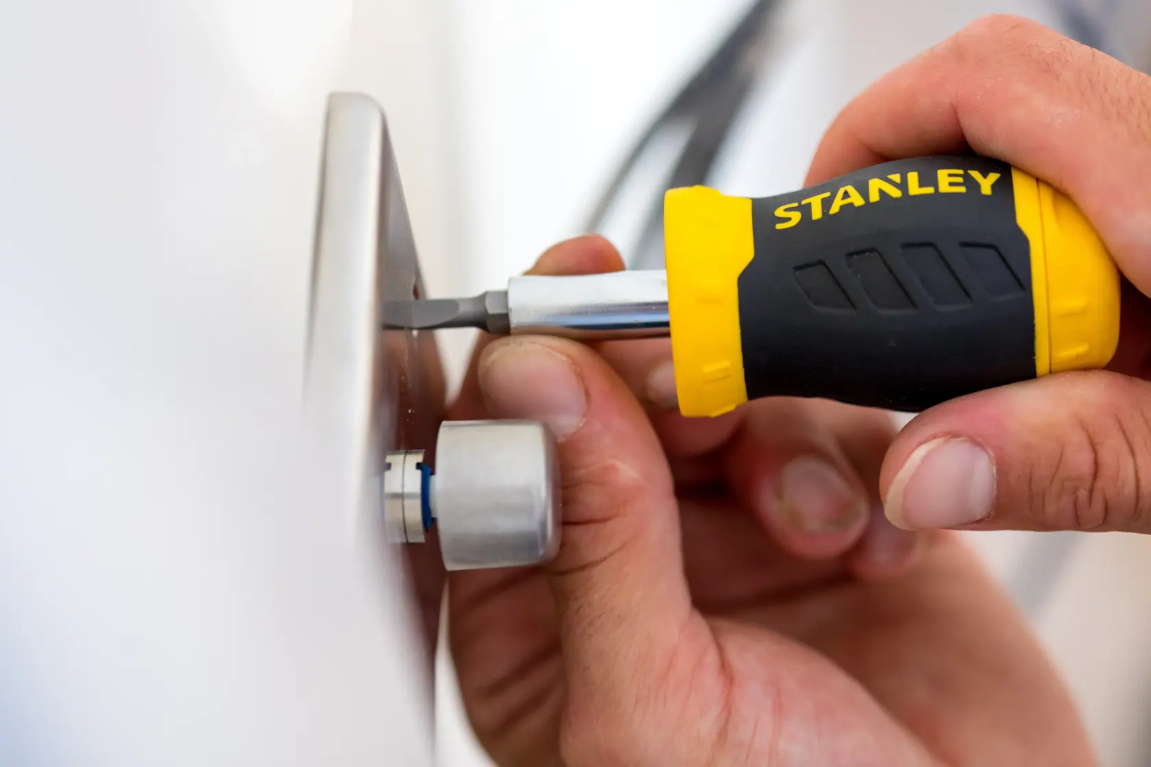 Cacciavite STANLEY 0-66-357 con manico giallo e nero utilizzato per stringere una vite su una piastra metallica.