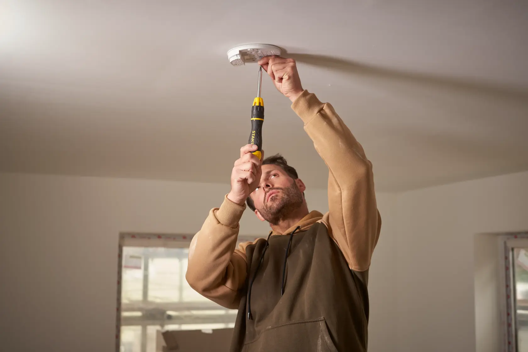 Foto del cacciavite STANLEY 0-68-010 utilizzato per installare un rilevatore di fumo sul soffitto bianco.