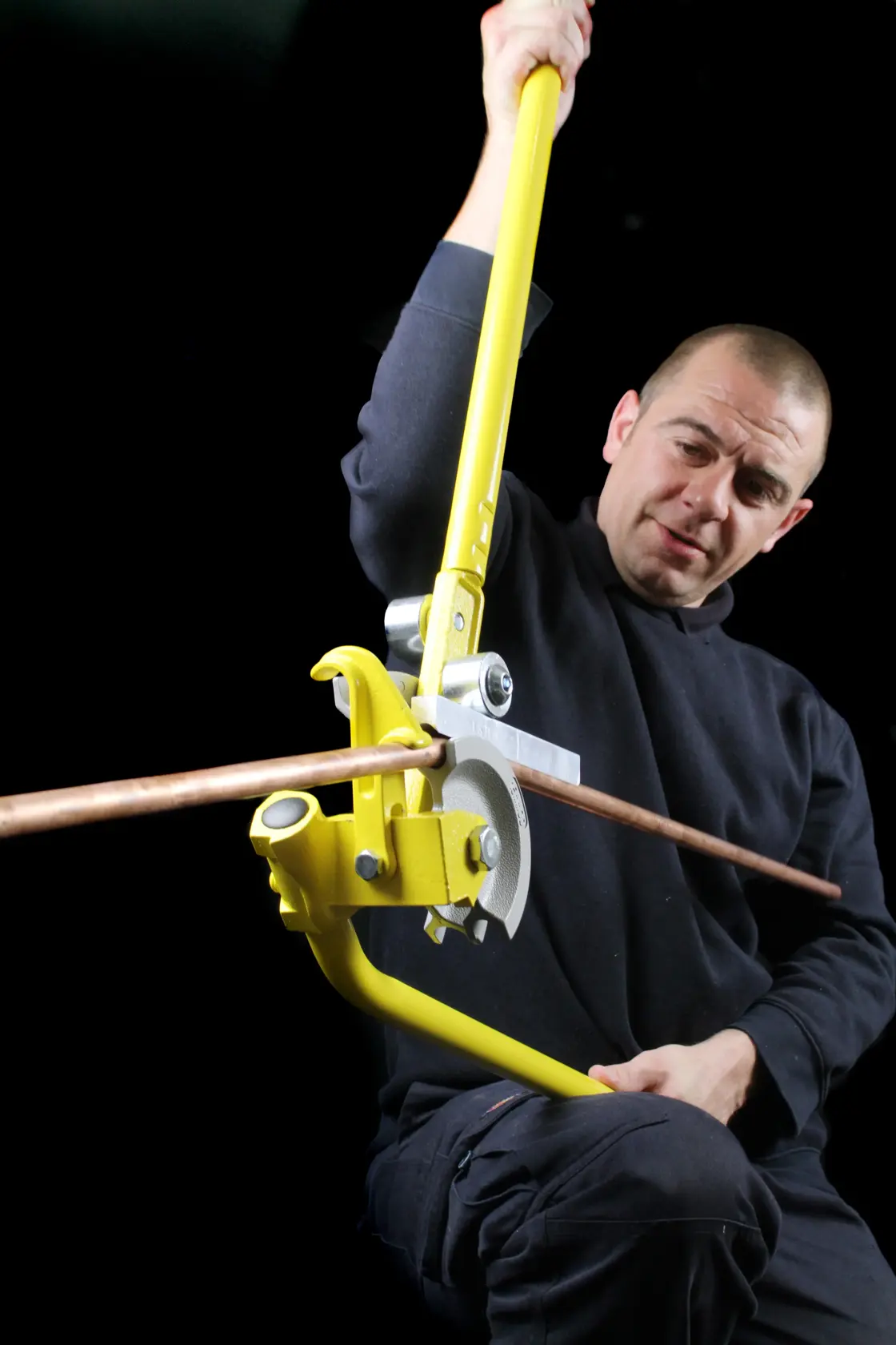 STANLEY 0-70-452 piegatubi manuale in uso per piegare un tubo di rame, su sfondo scuro.