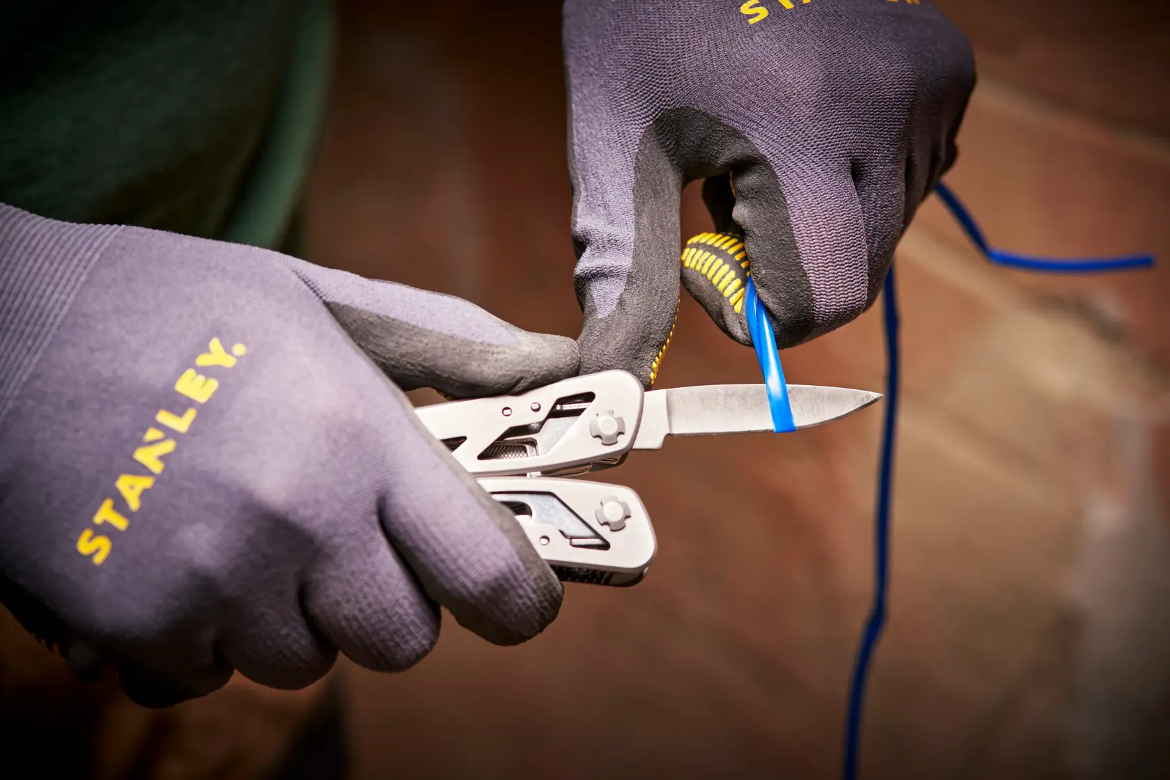 STANLEY 0-84-519 multitool che taglia filo blu, primo piano, usato con guanti STANLEY.