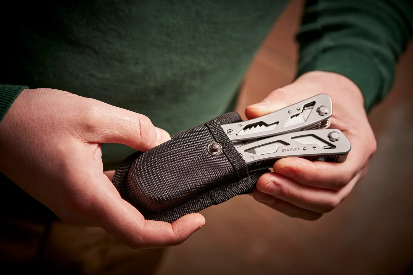 STANLEY 0-84-519 multitool in custodia nera tenuta in mano, foto ravvicinata.