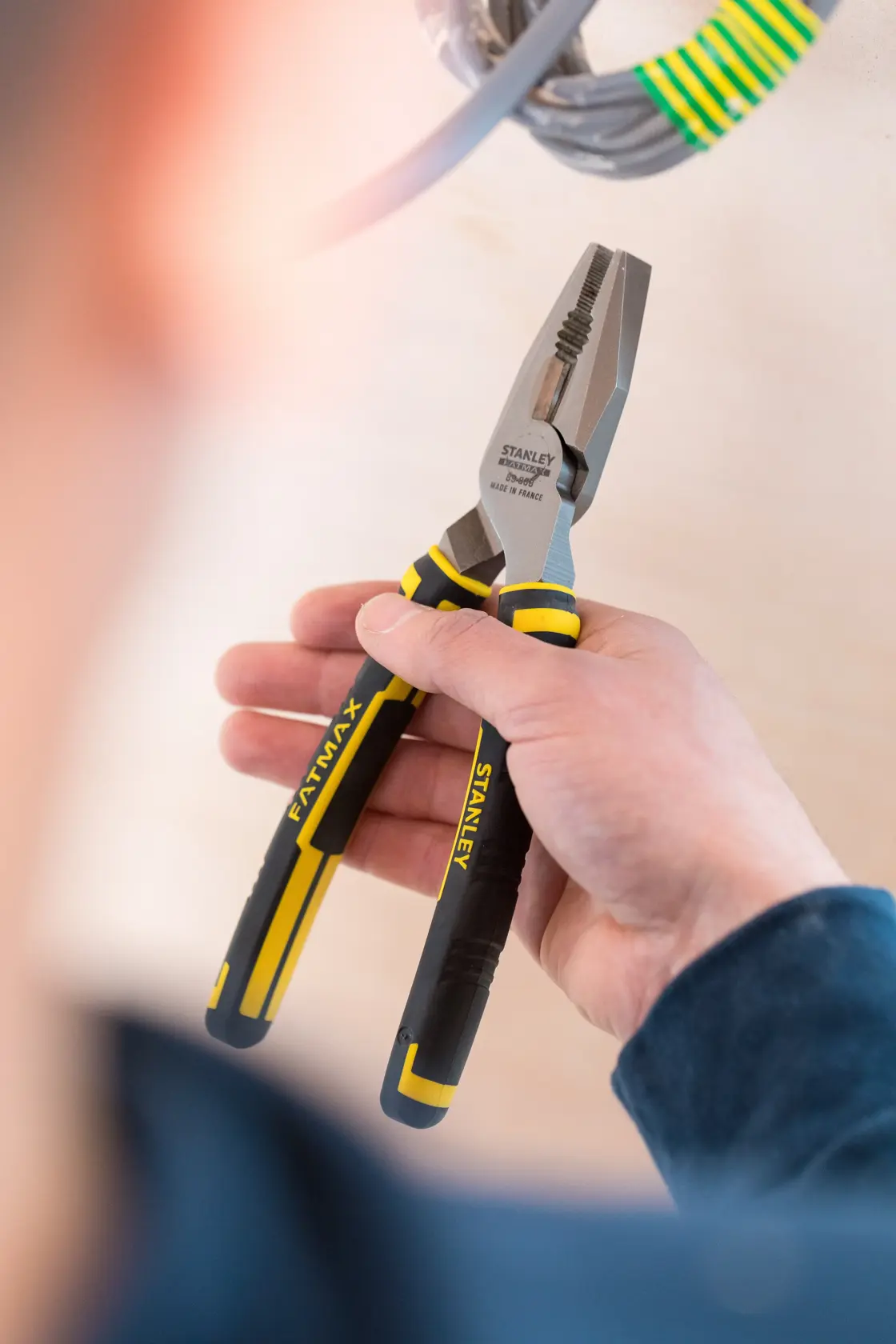 STANLEY 0-89-868 pinza con manici neri e gialli, tenuta in mano vicino a cavi elettrici.