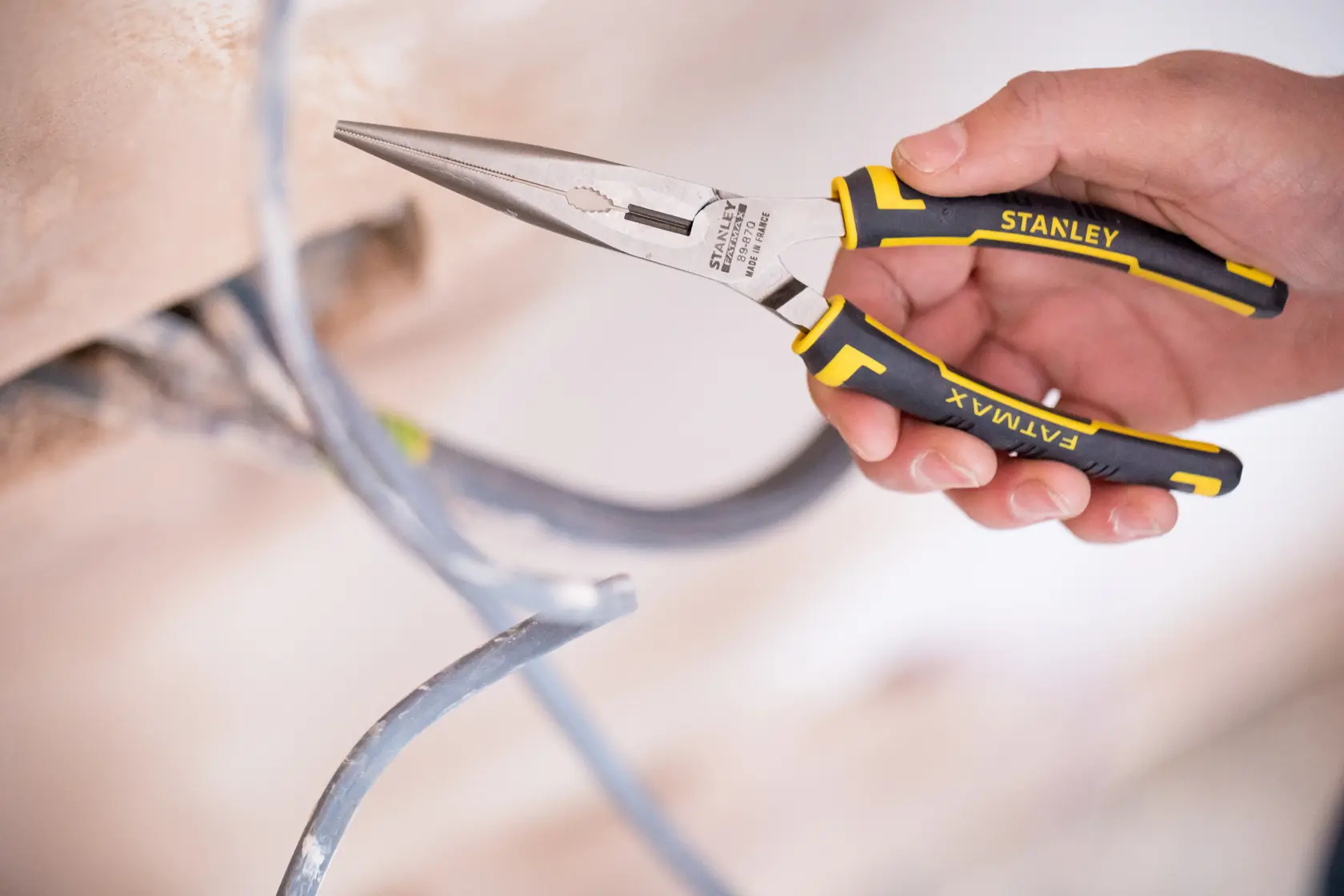Stanley 0-89-870 FATMAX pinza a becchi lunghi nera e gialla tiene un cavo elettrico.