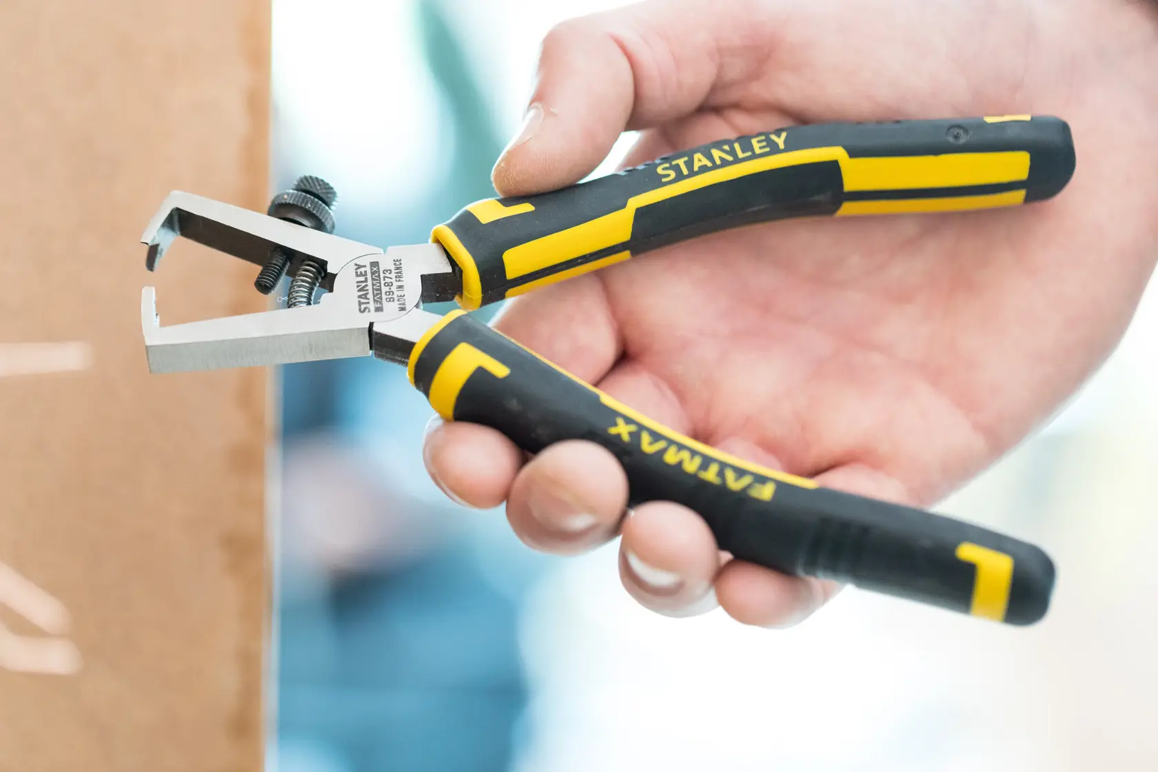 Pinza spelacavi STANLEY 0-89-873 con manico nero e giallo, tenuta in mano, vista laterale.