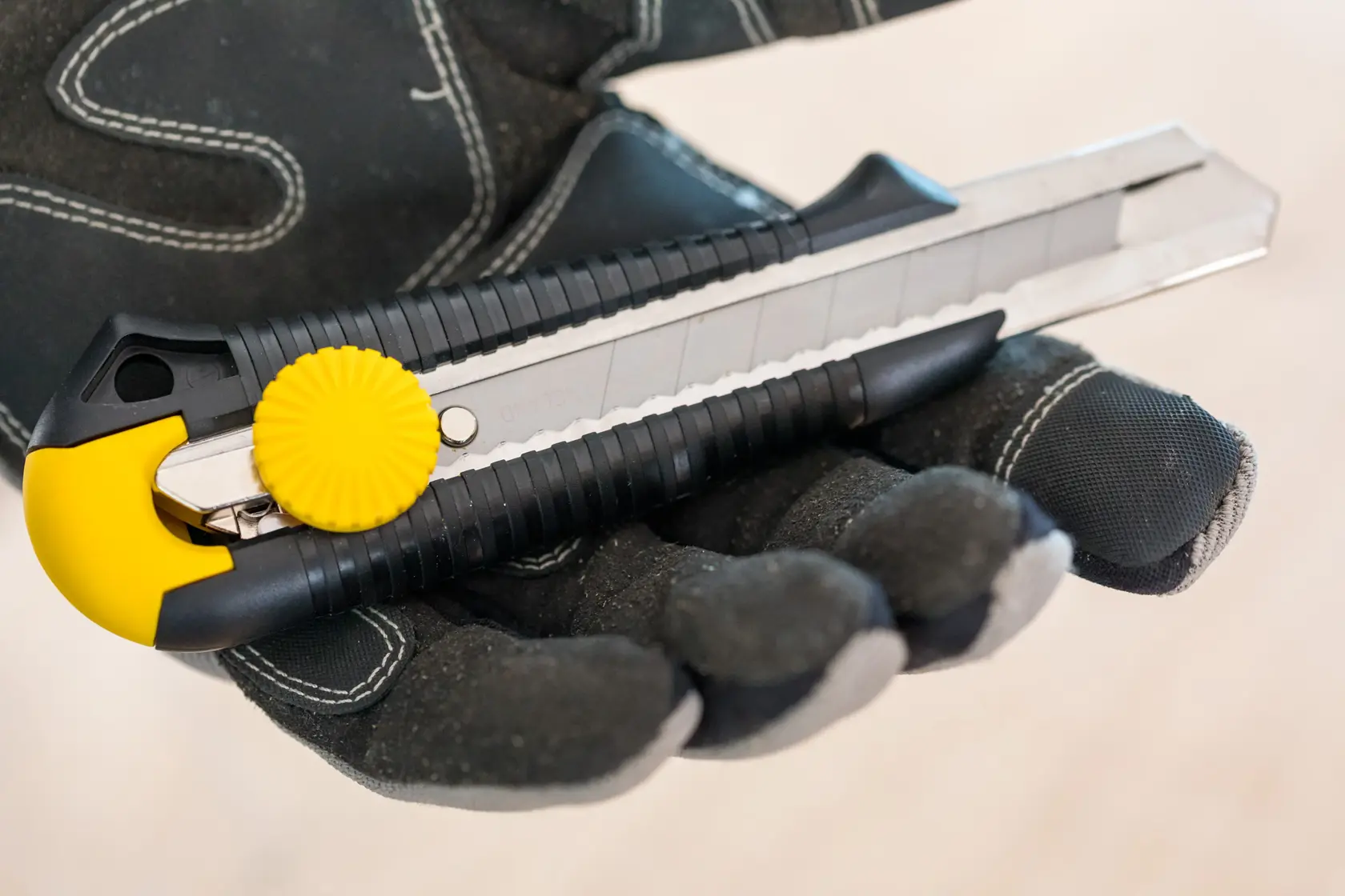 STANLEY 1-10-418 coltello universale con pomello giallo, tenuto da mano guantata, fotografia ravvicinata.