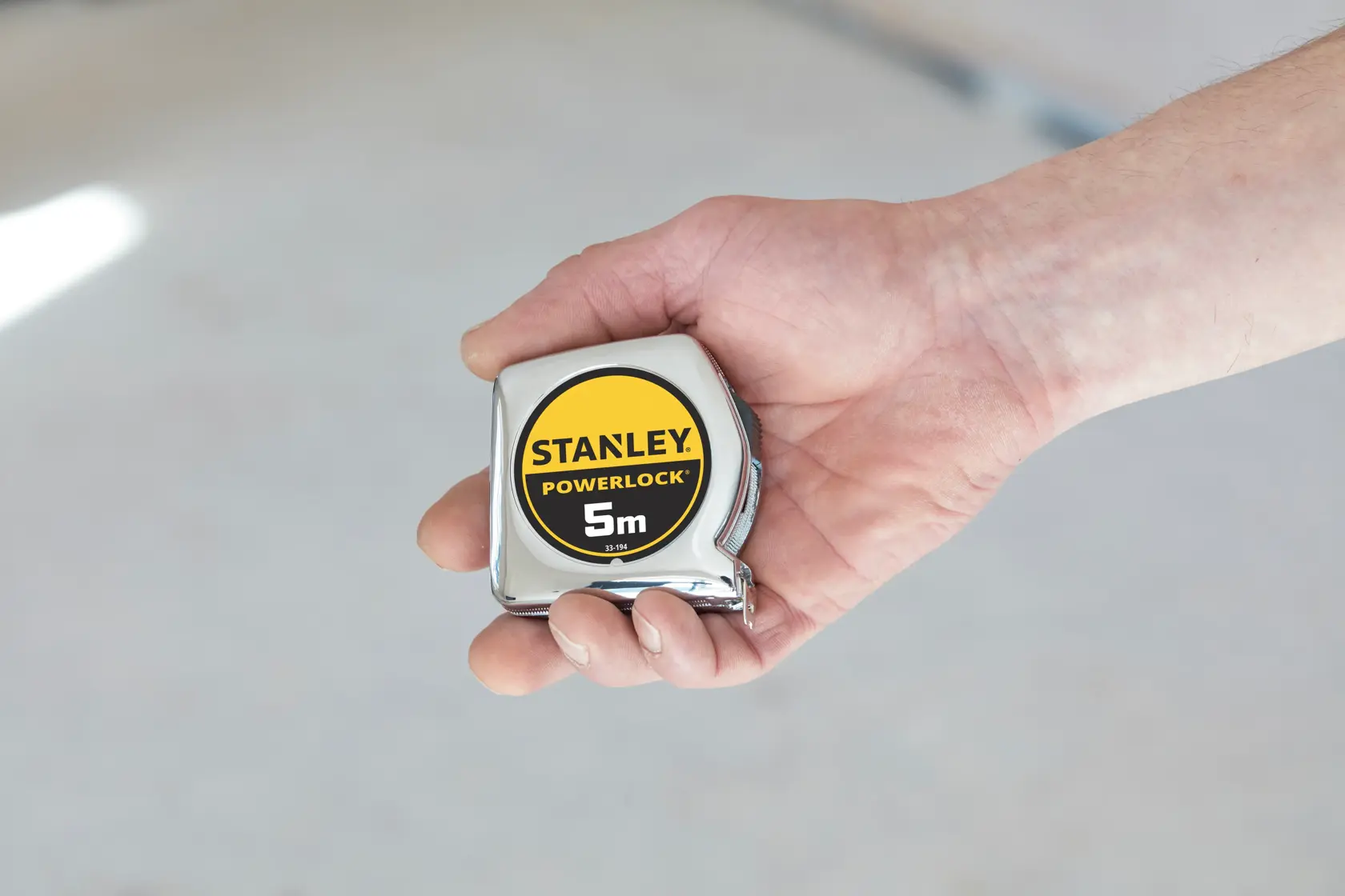 Metro a nastro STANLEY 1-33-194 PowerLock 5m tenuto in mano, vista ravvicinata.
