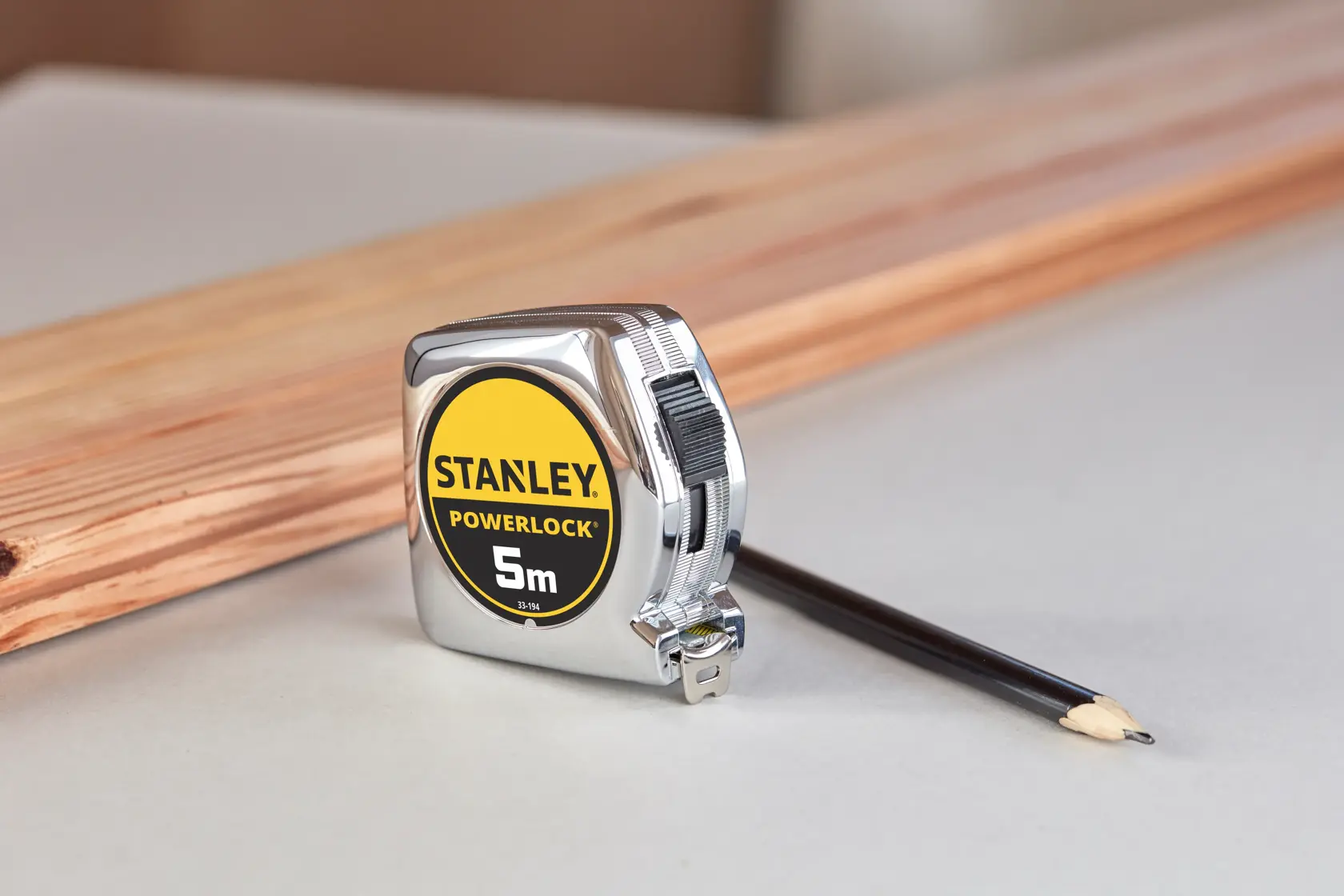 STANLEY 1-33-194 metro a nastro PowerLock 5m, fotografia con matita e legno sullo sfondo.