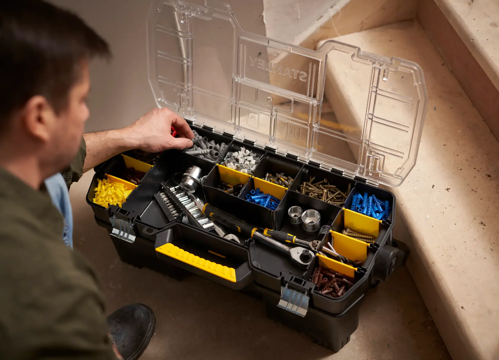 Box organizer STANLEY 1-97-514 aperta con utensili e accessori assortiti, foto dall’alto vicino alle scale.