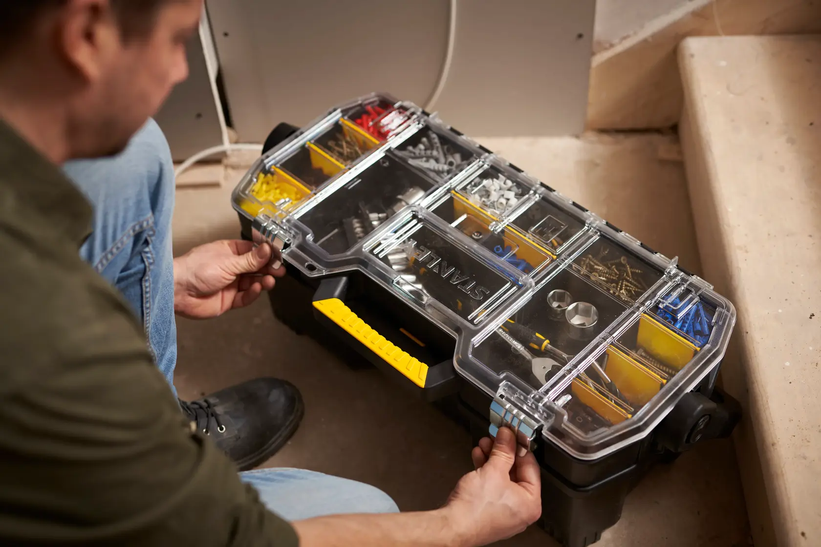 Organizer STANLEY 1-97-514 con coperchio trasparente, manico giallo, scomparti con ferramenta, usato in cantiere.