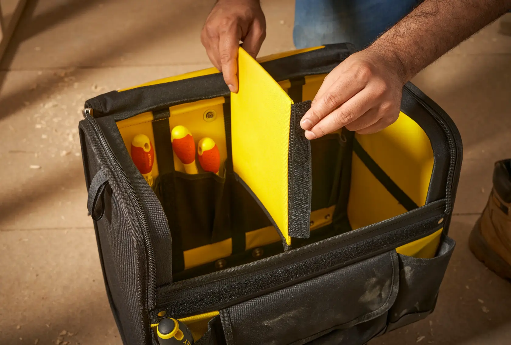 STANLEY 1-97-515 borsa porta attrezzi con divisore interno giallo, mano che tiene il divisore, angolo frontale.