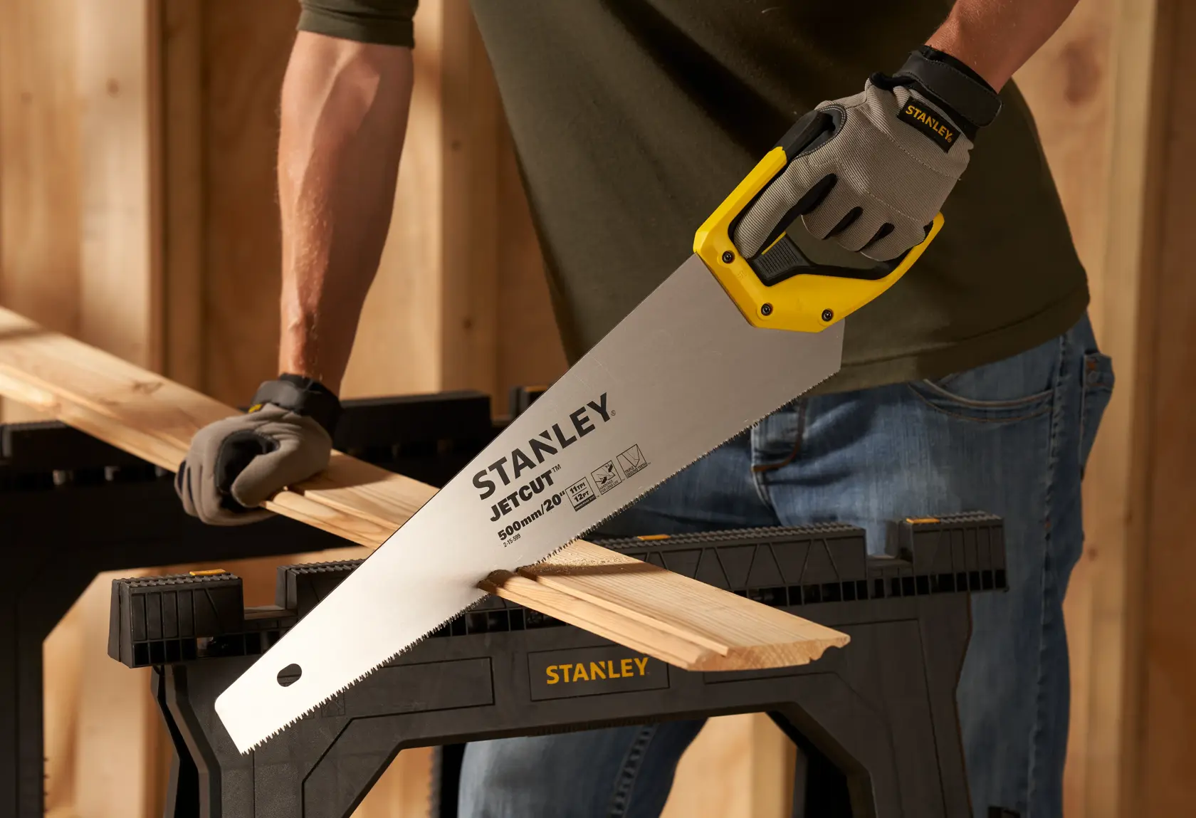 Foto di STANLEY 2-15-599 sega manuale che taglia legno su cavalletto, dettaglio della lama e manico giallo.