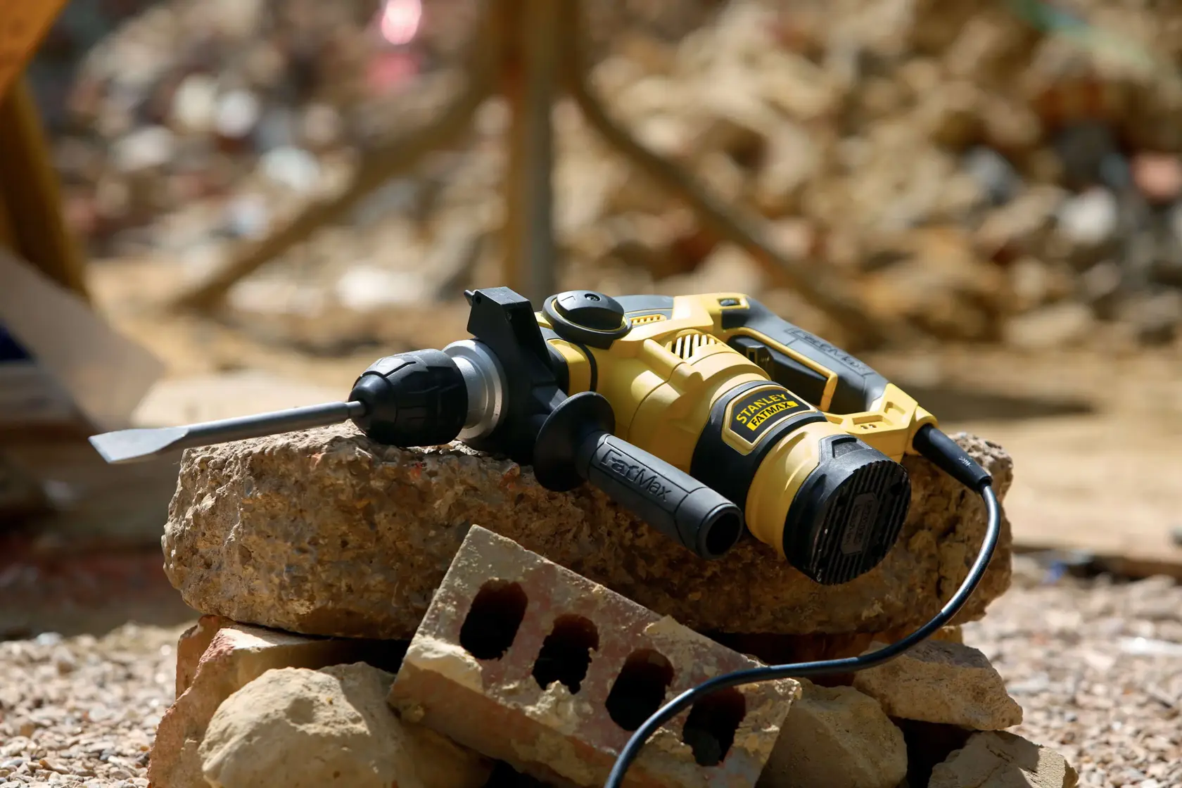 Martello rotativo STANLEY FME1250K con scalpello su macerie edili, mostrato in esterno.