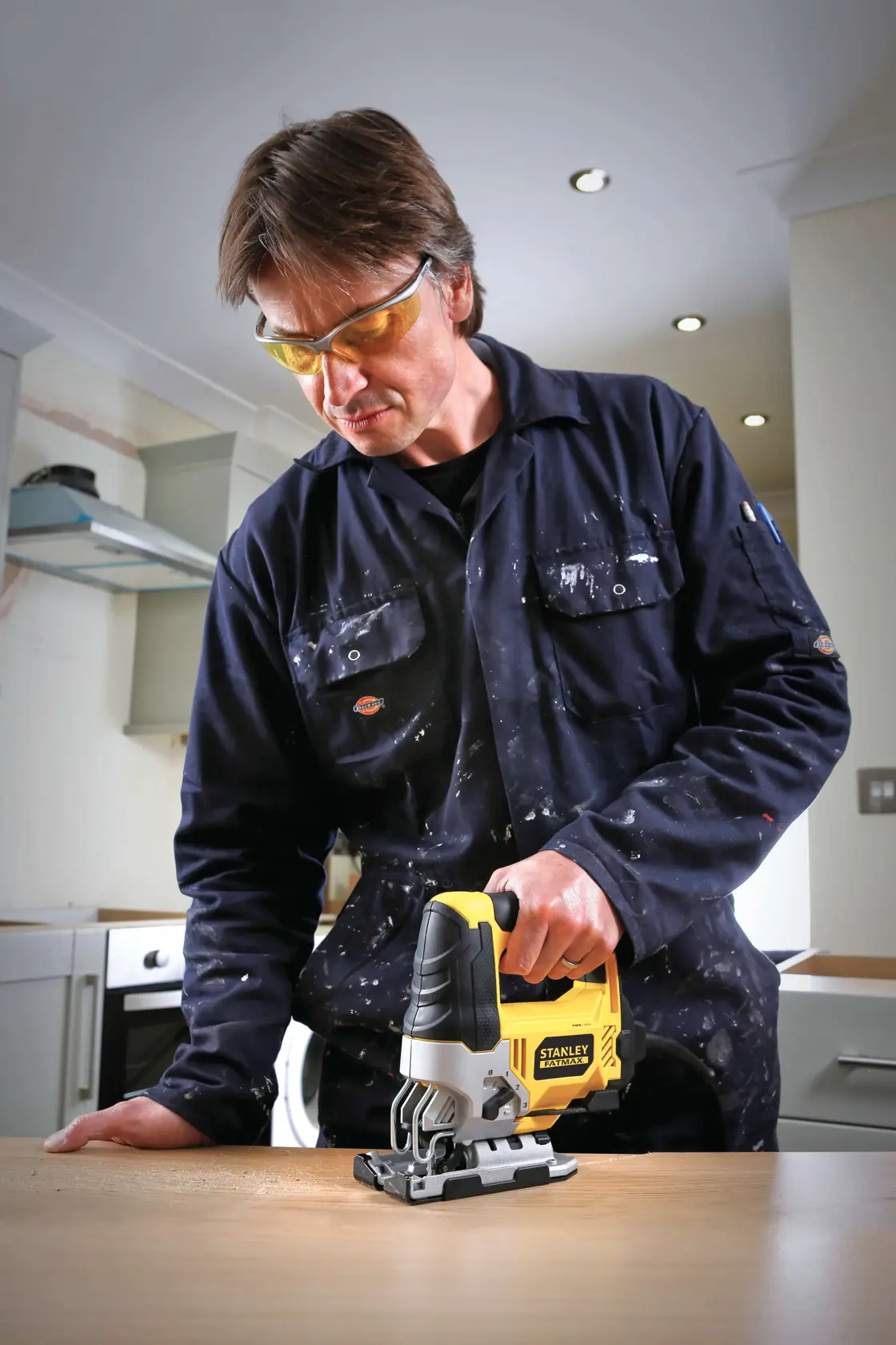 STANLEY FME340K seghetto alternativo tenuto da persona in tuta blu taglia legno su banco in cucina.