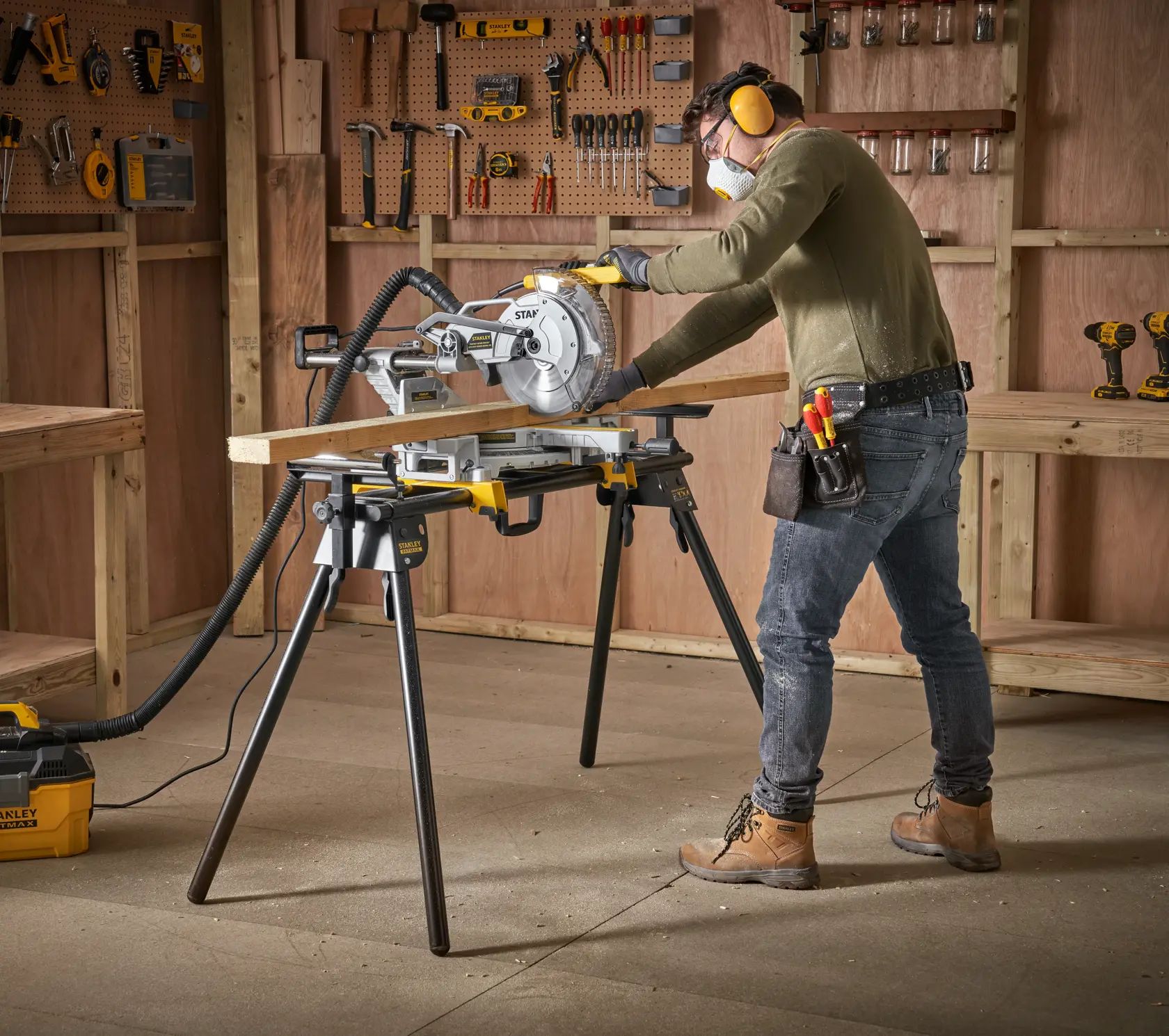 Foto della troncatrice STANLEY FME790-XJ su supporto in officina, operaio taglia una tavola di legno.
