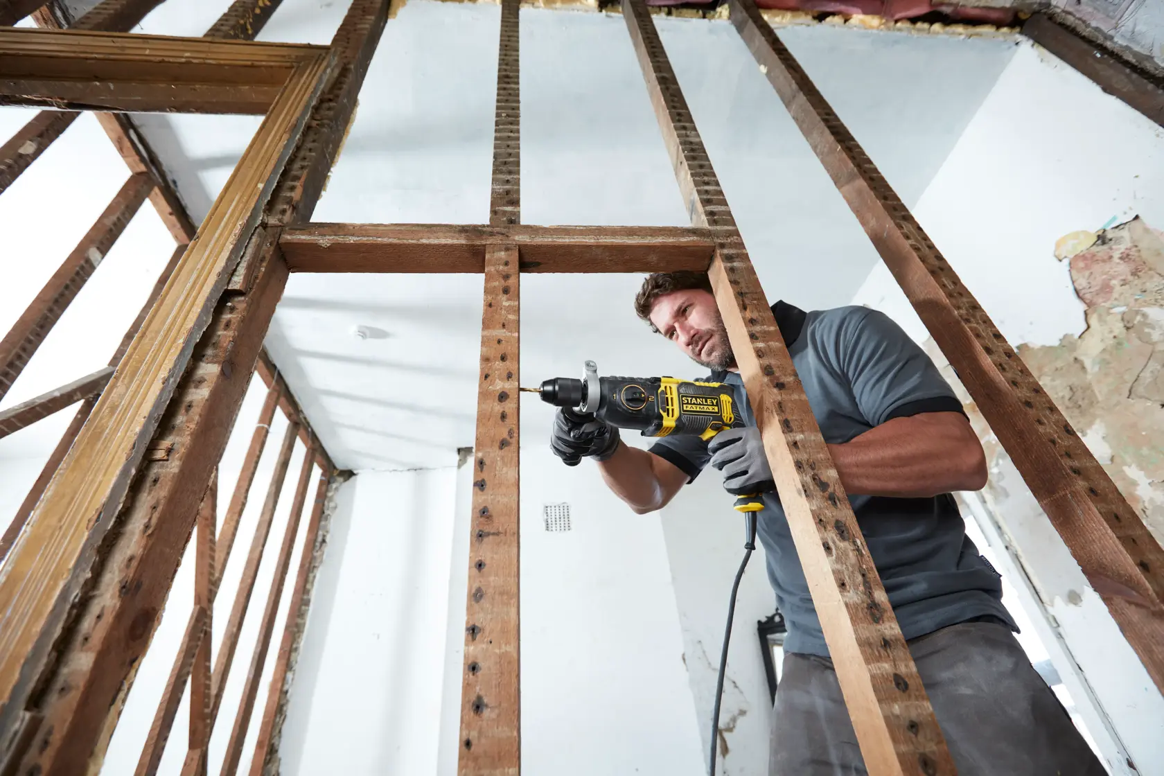 Foto del trapano a percussione STANLEY FMEH1100K in uso su struttura in legno, cantiere, vista laterale.