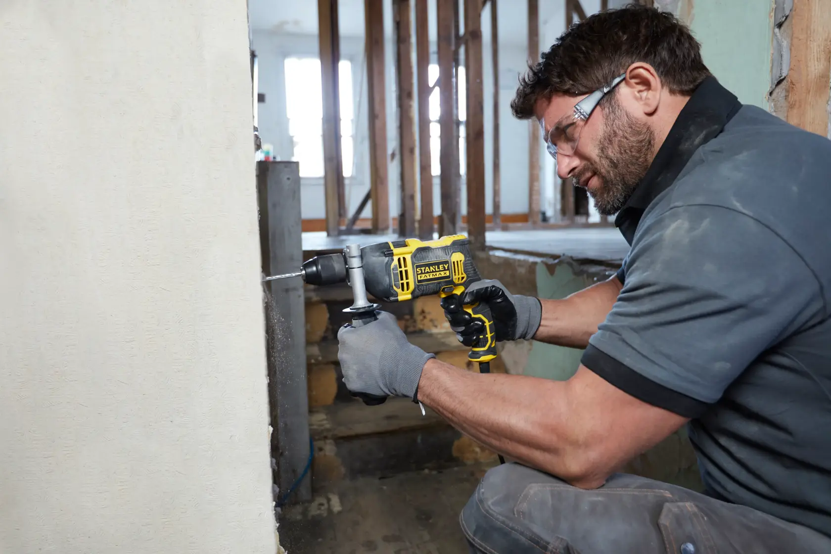Foto di lavoratore che utilizza il trapano a percussione con filo STANLEY FMEH750K per forare una parete in cemento in cantiere.