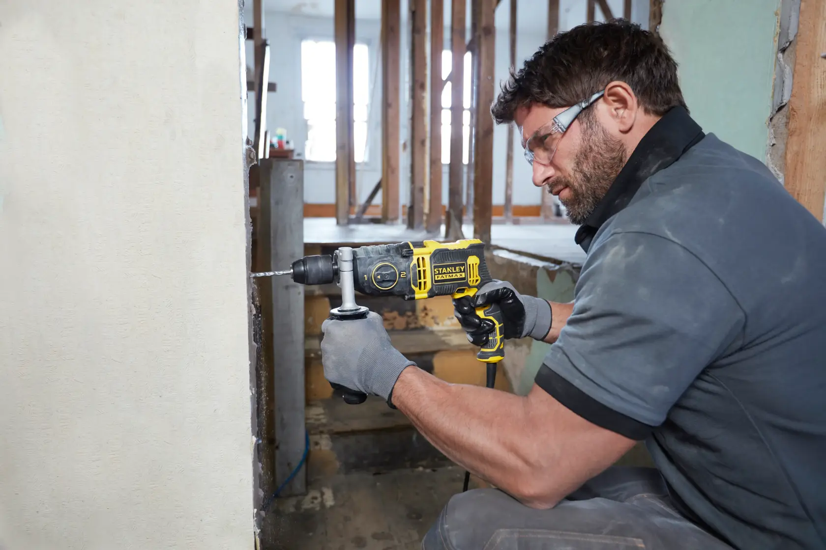 Trapano a percussione STANLEY FMEH850K in uso, fora un muro, ambiente di cantiere.