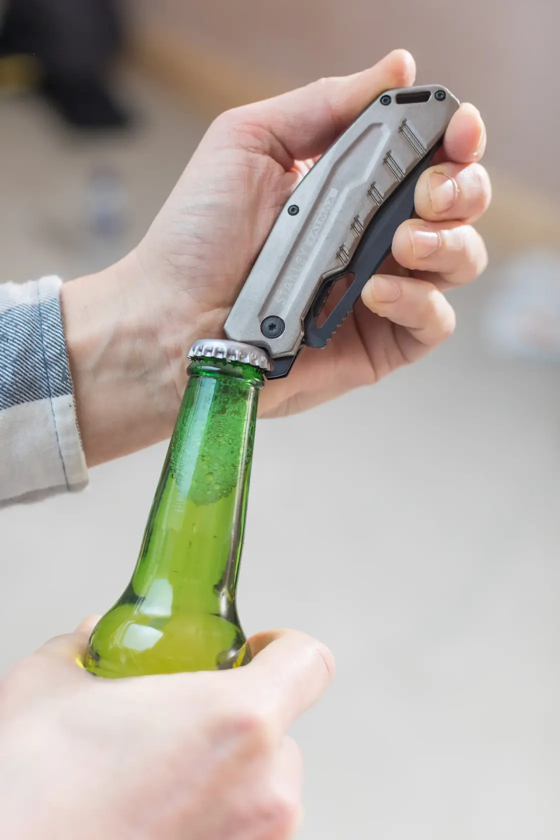 Foto del coltello pieghevole STANLEY FMHT0-10312 usato per aprire una bottiglia di vetro verde.