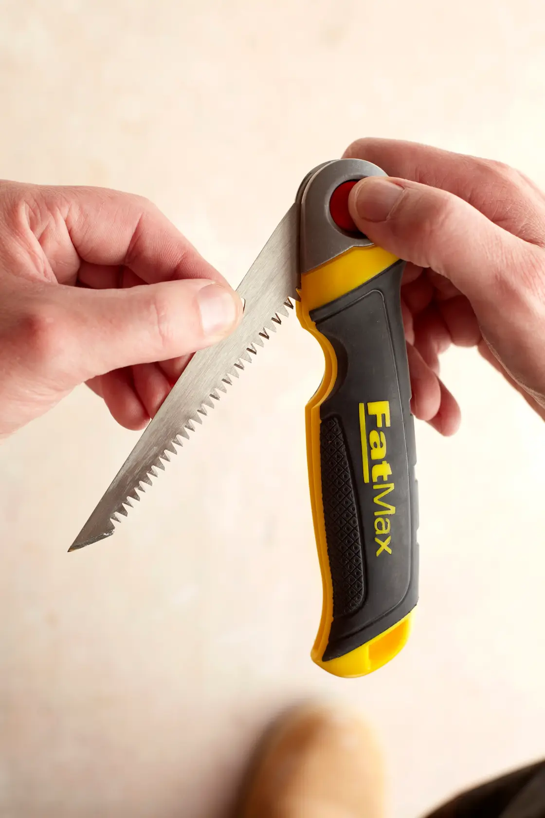 STANLEY FMHT0-20559 seghetto pieghevole con manico FatMax nero e giallo, tenuto in mano, primo piano.