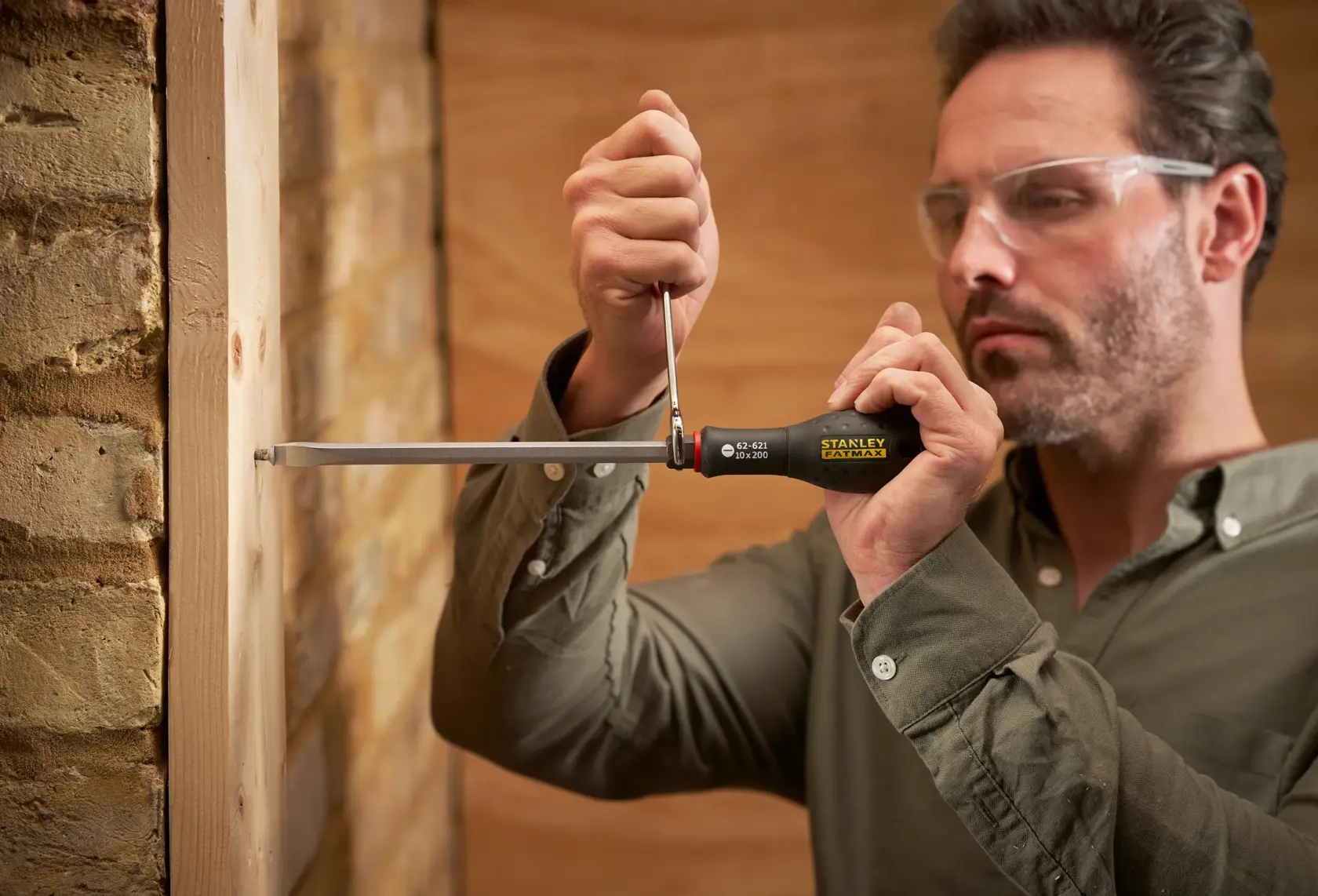 STANLEY FMHT0-62621 cacciavite usato per avvitare una vite nel legno, primo piano dello strumento in mano.