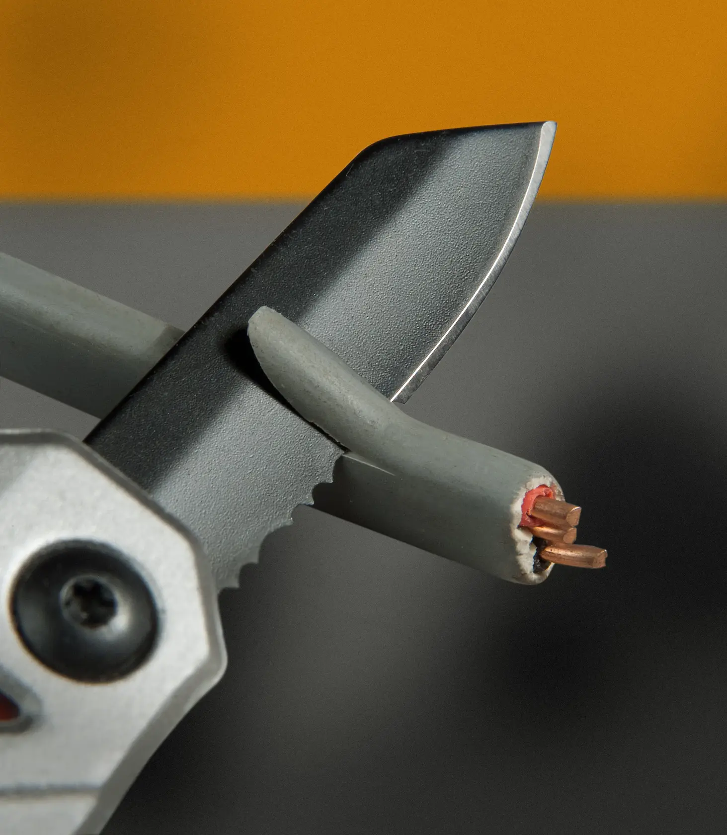 Lama dentata STANLEY FMHT0-72414 che taglia un cavo elettrico grigio, vista ravvicinata.
