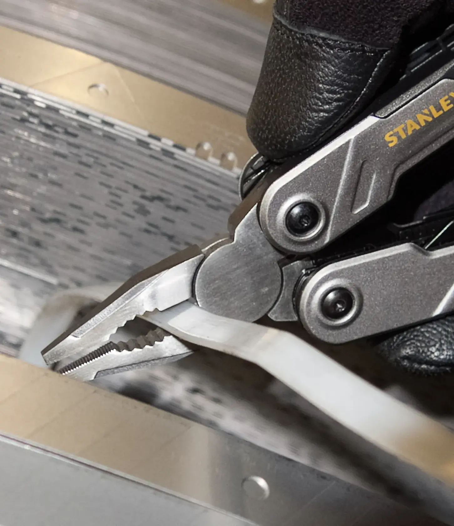 STANLEY FMHT0-72414 pinza multitool che afferra un cavo bianco, foto ravvicinata.
