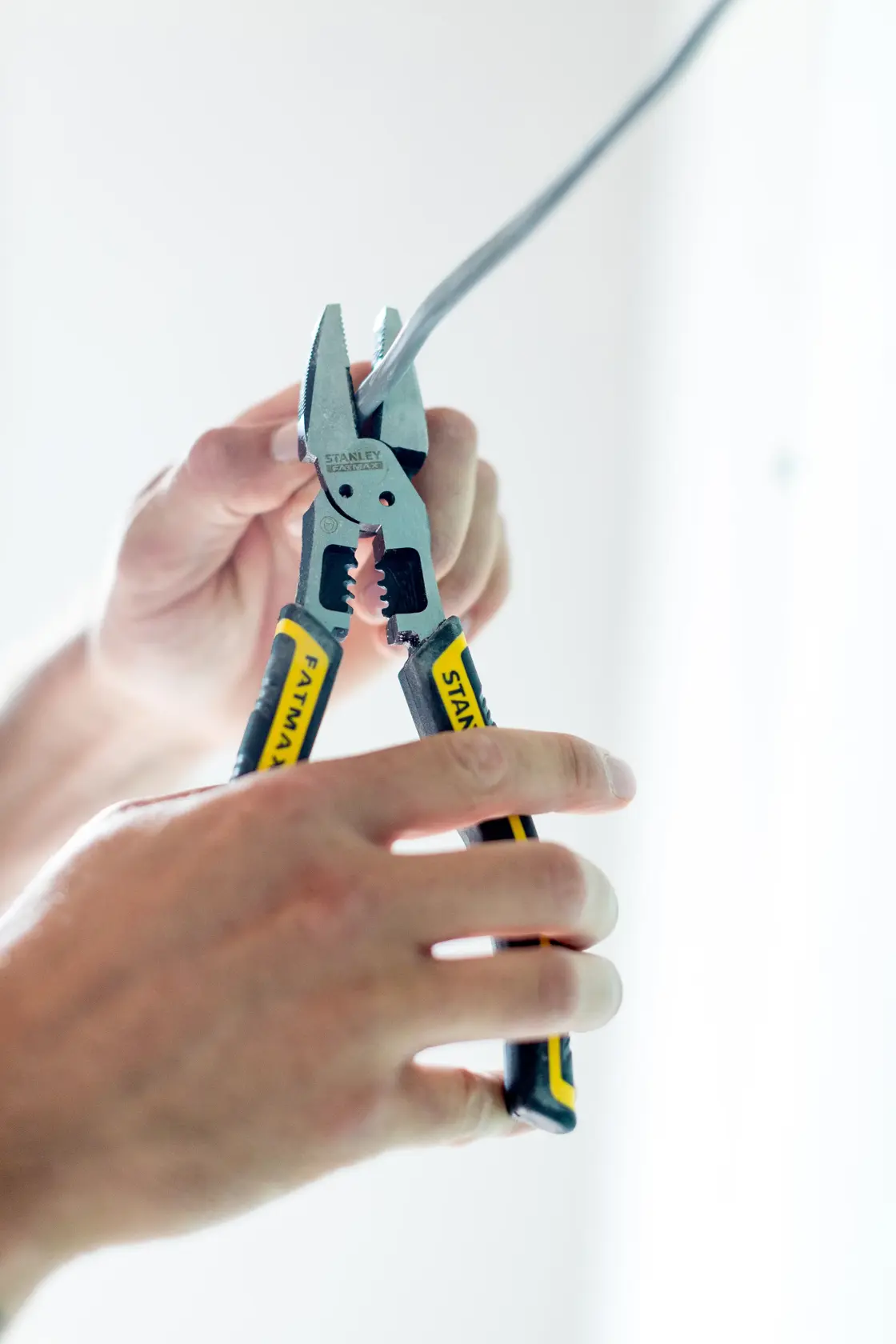 STANLEY FMHT0-75469 FATMAX pinza con manici gialli e neri spella un cavo elettrico a mano.