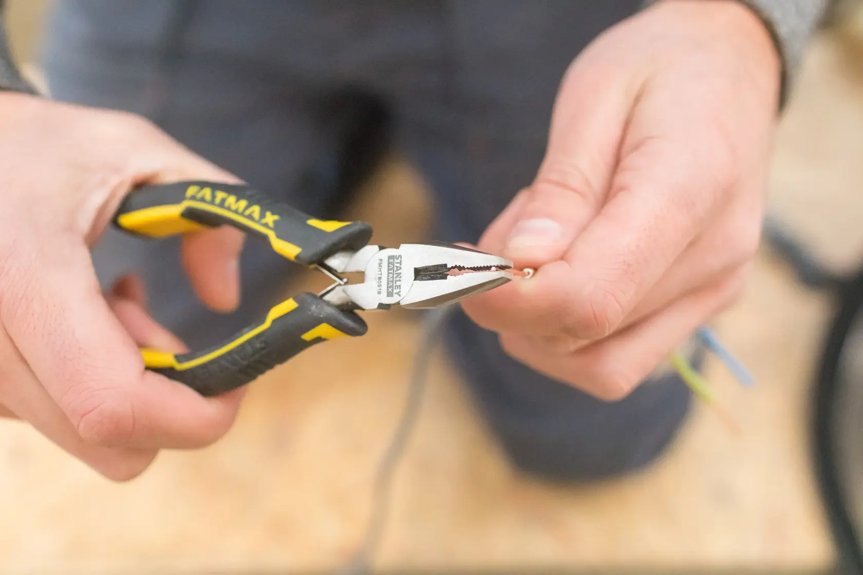 Pinza STANLEY FMHT0-80524 con impugnatura gialla e nera che afferra un filo, primo piano in mano.