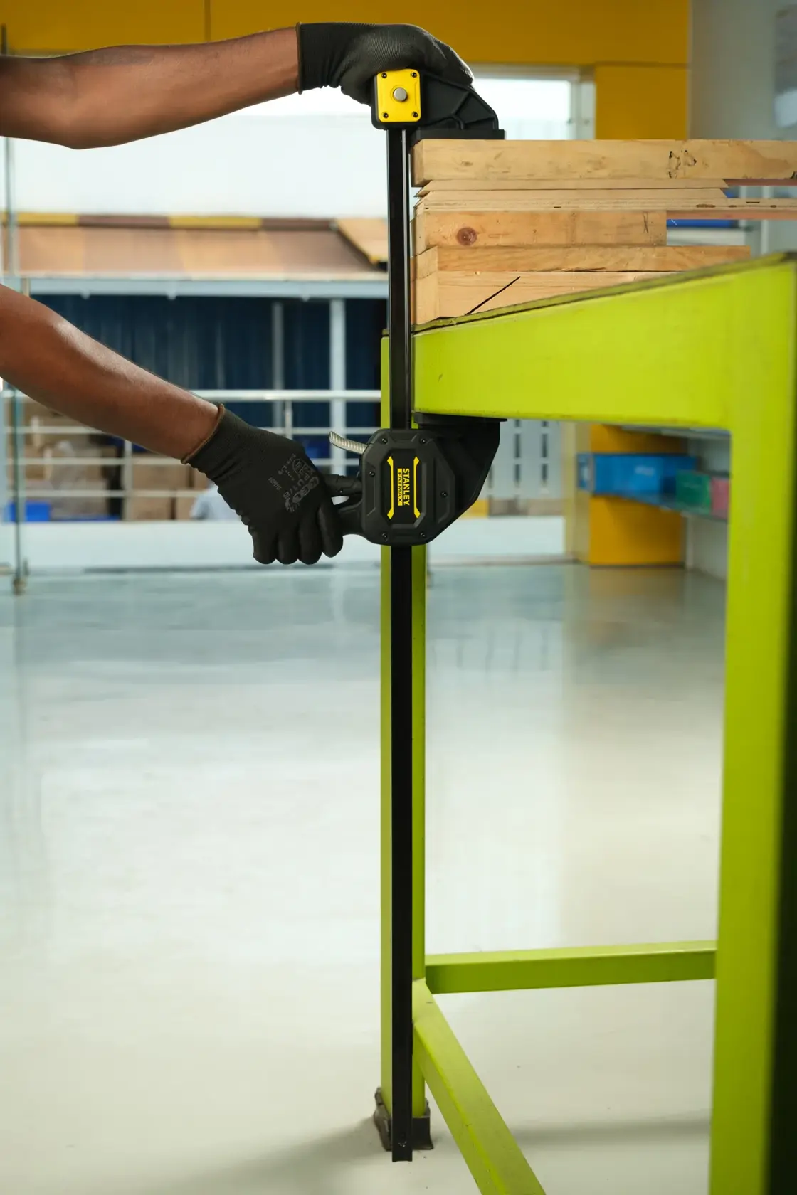Morsetto Stanley FMHT0-83241 in uso su banco da lavoro verde per fissare legno, angolo laterale ravvicinato.