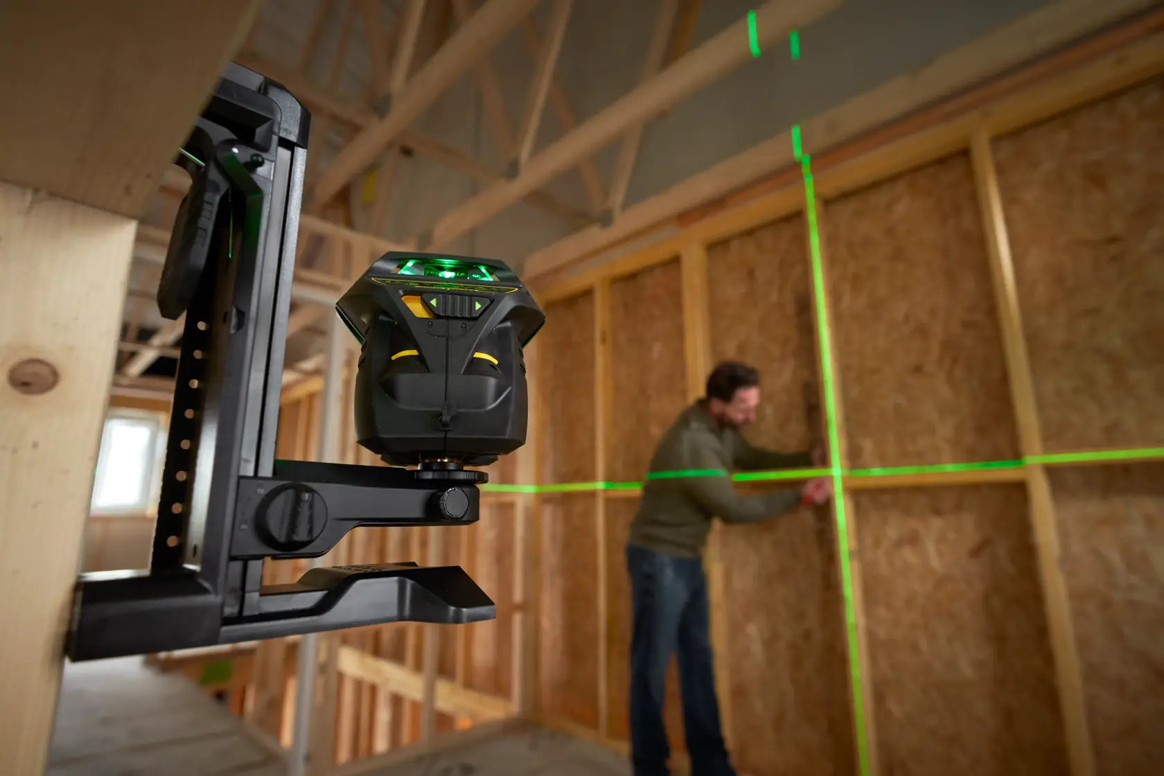 Livella laser STANLEY FMHT1-77356 che proietta linee verdi su una parete in cantiere, vista laterale.