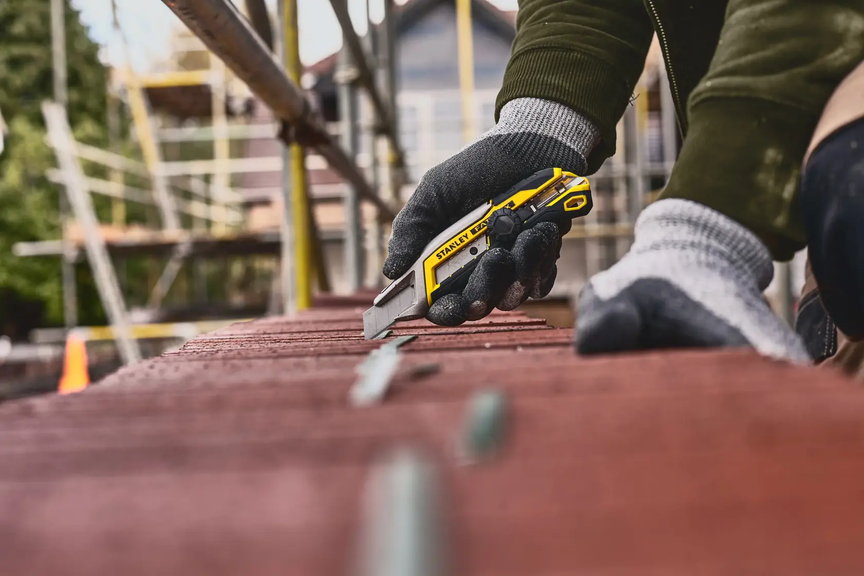 Stanley FMHT10592-0 cutter giallo e nero usato da mano con guanto in cantiere.