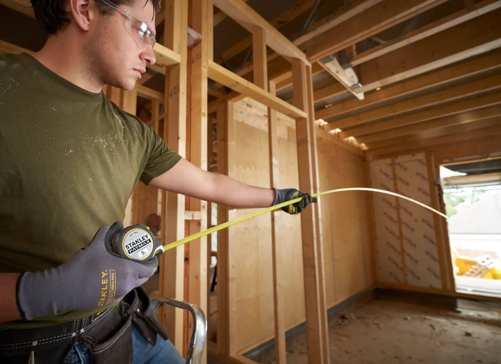 Stanley FMHT38214-0 metro a nastro usato da un operatore con guanti in un cantiere con struttura in legno.