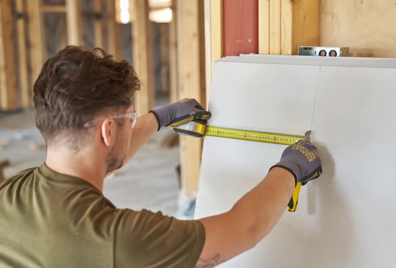 Foto di persona che utilizza il metro a nastro STANLEY FMHT38214-0 per misurare un pannello in cartongesso sul cantiere.