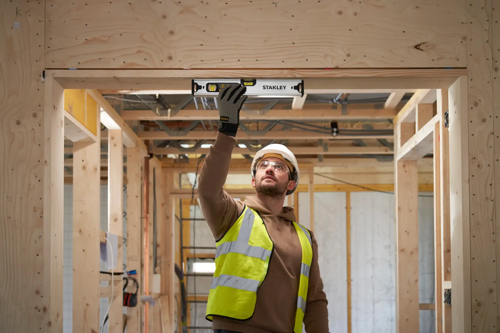 Foto di un operaio che utilizza una livella STANLEY FMHT43670-1 su un telaio di porta in legno in un cantiere.