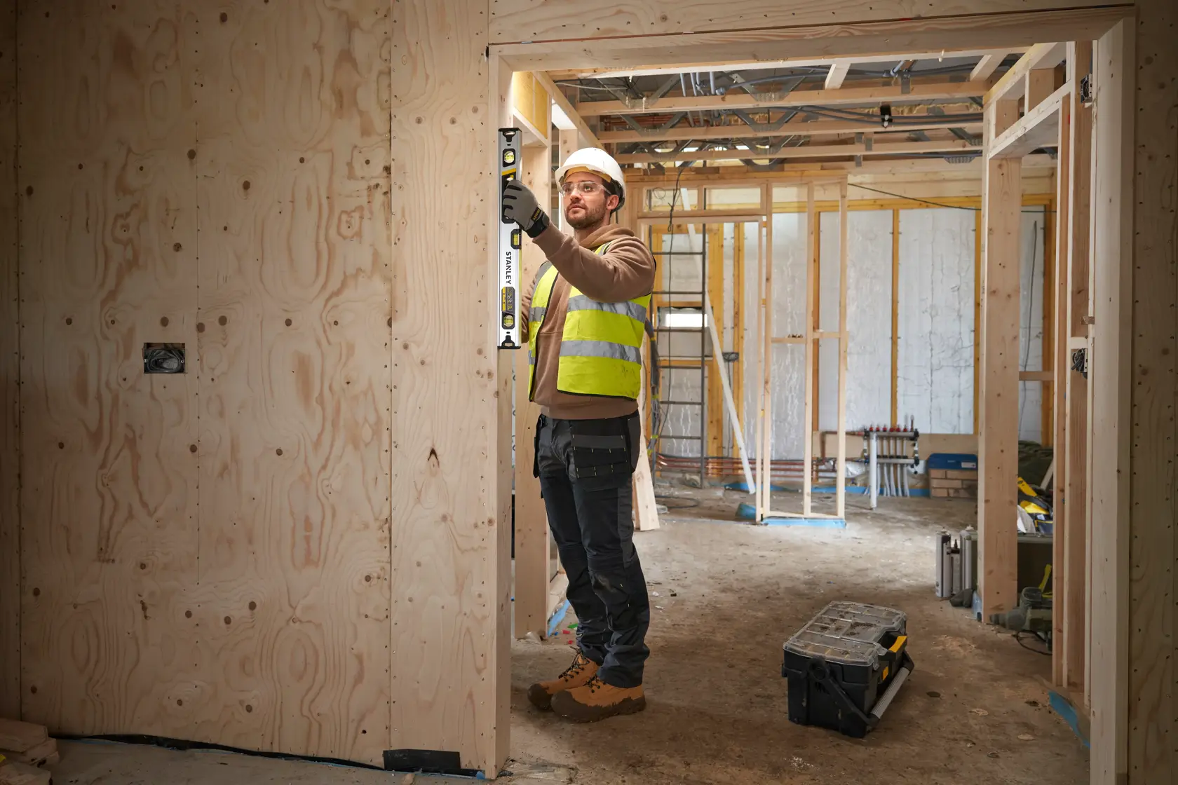 STANLEY FMHT43673-1 livella a bolla usata da operaio su telaio di porta in legno in cantiere.