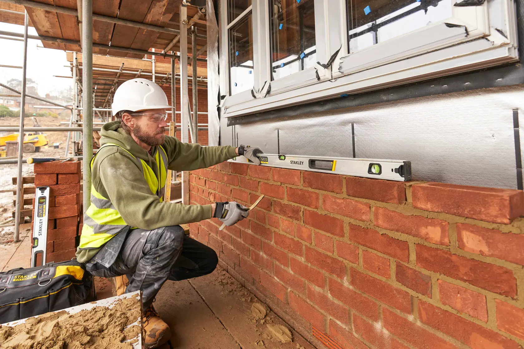 Livella STANLEY FMHT43676-1 usata da un muratore per controllare l’allineamento di una parete in mattoni sul cantiere.