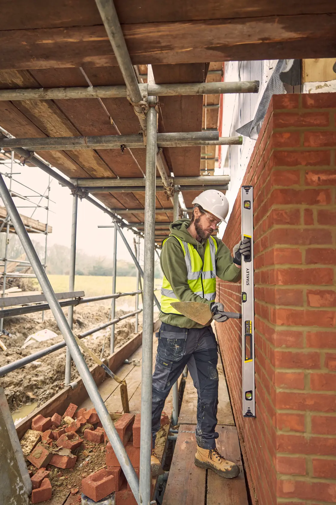 Livella STANLEY FMHT43677 usata da un operaio per verificare l’allineamento di un muro in mattoni in cantiere.