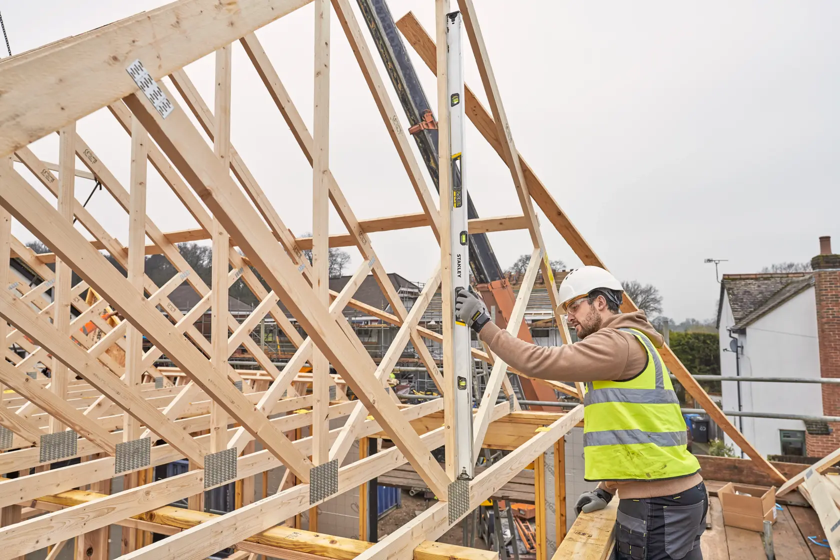 Livella STANLEY FMHT43678-1 utilizzata da un operaio su una struttura in legno, cantiere esterno.