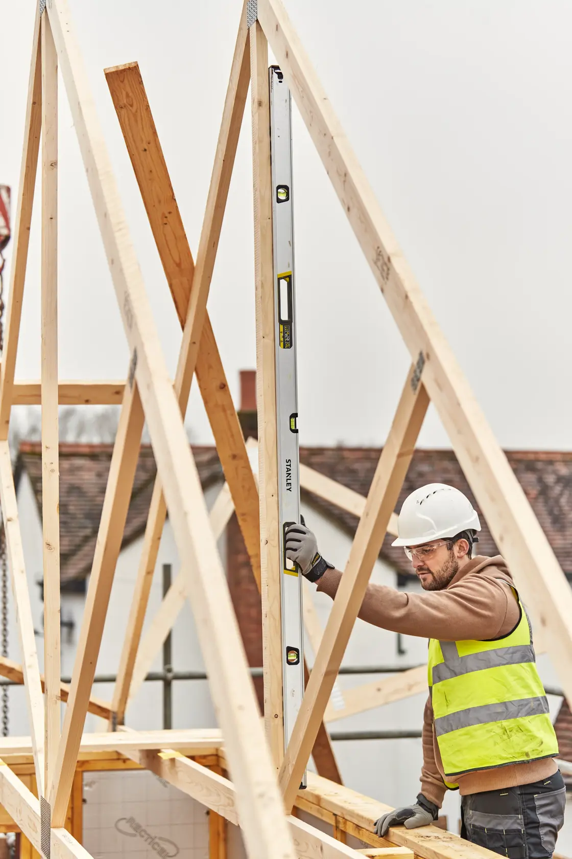 Livella STANLEY FMHT43679-1 usata verticalmente da un operaio su struttura in legno in cantiere.