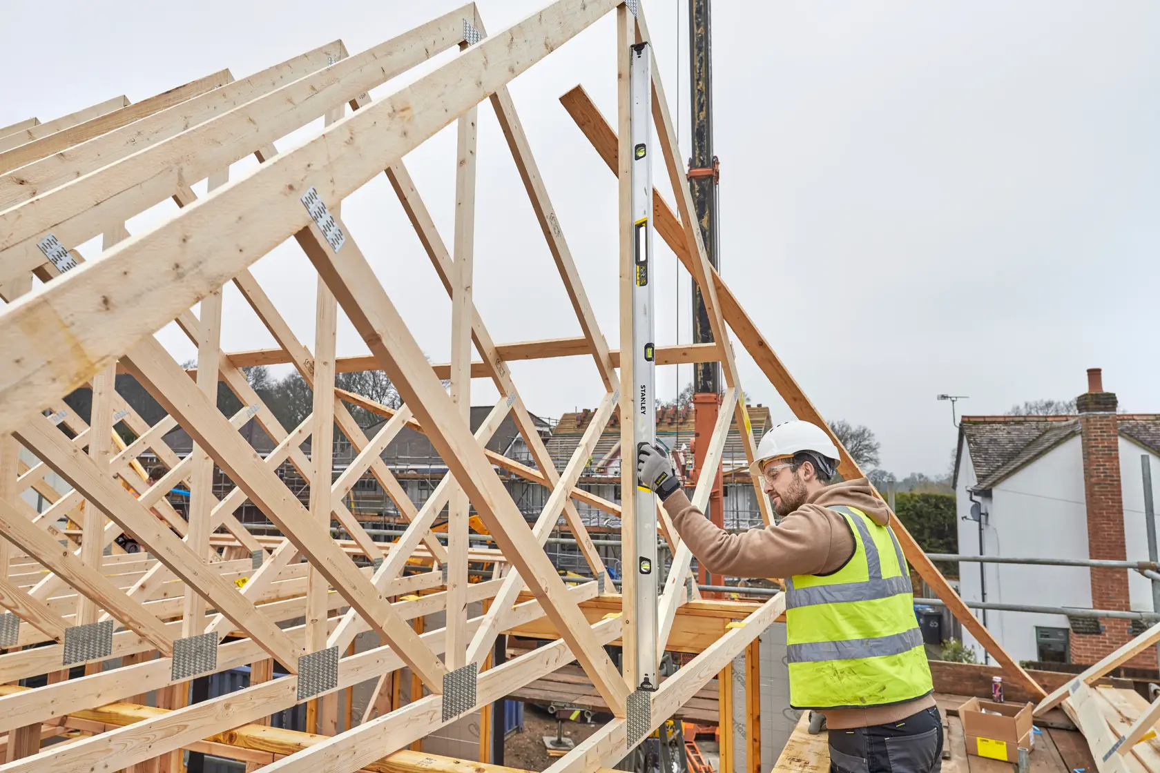 Livella STANLEY FMHT43680-1 usata da un operaio per misurare telai in legno su un cantiere.