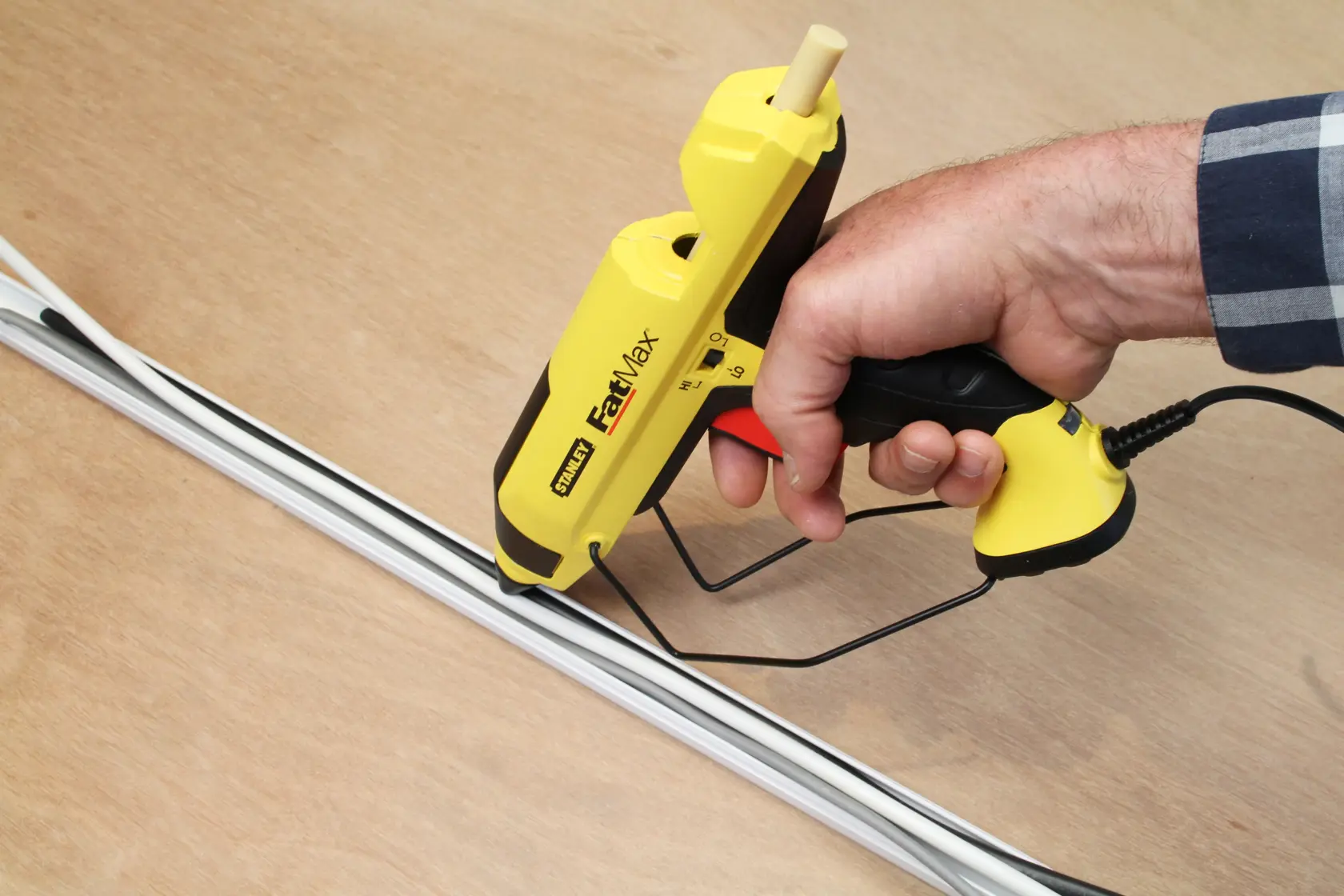 STANLEY FMHT6-70418 pistola per colla gialla usata per applicare adesivo su una cornice bianca su legno.