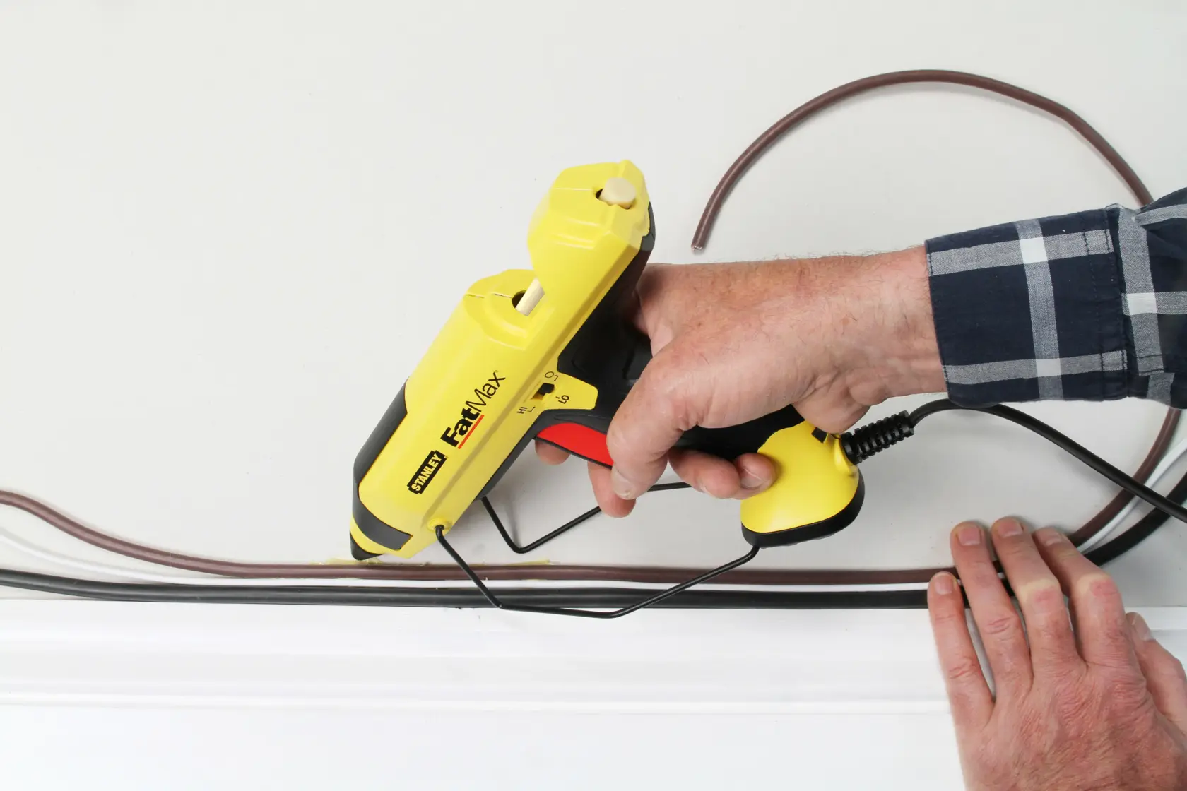 STANLEY FMHT6-70418 pistola per colla FastMax gialla usata per installare cavi su una parete.